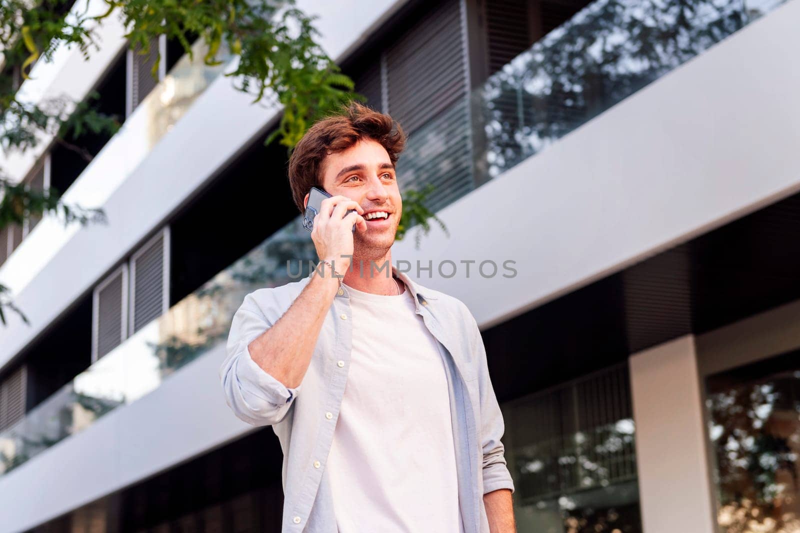 man smiling happy while walking in a good mood talking on cell phone, concept of technology of communication and urban lifestyle, copyspace for text