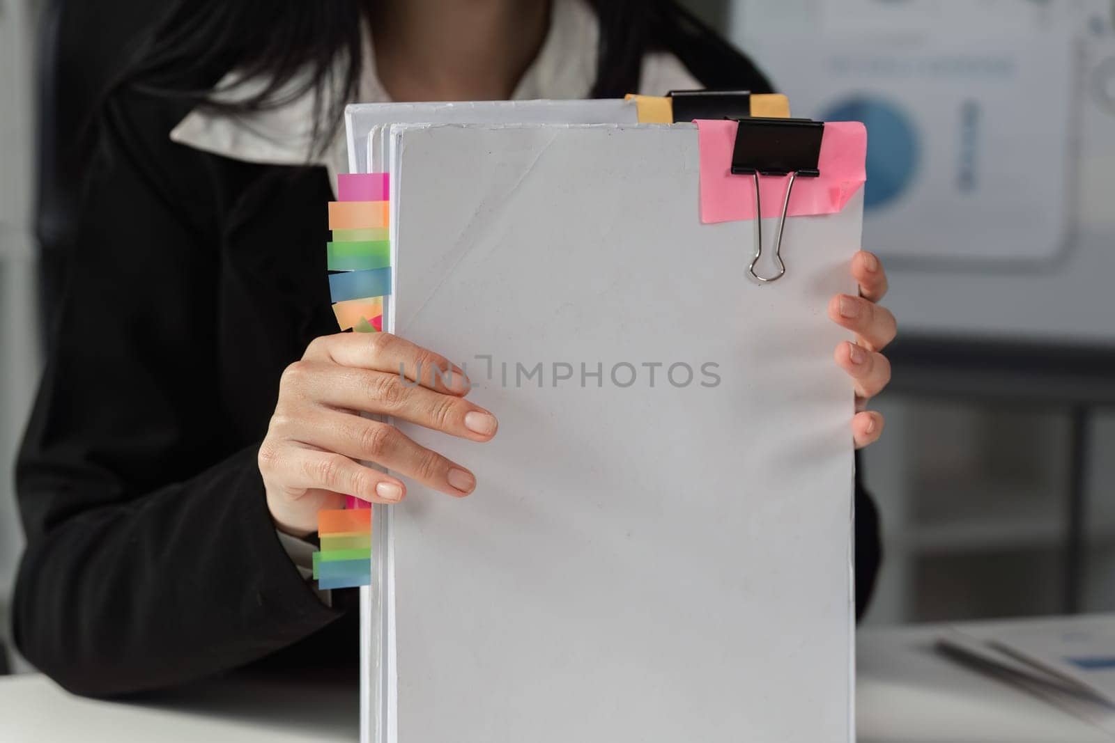 An accountant displays a well-organized stack of financial documents, using colorful tabs to enhance accessibility and efficiency in her work.