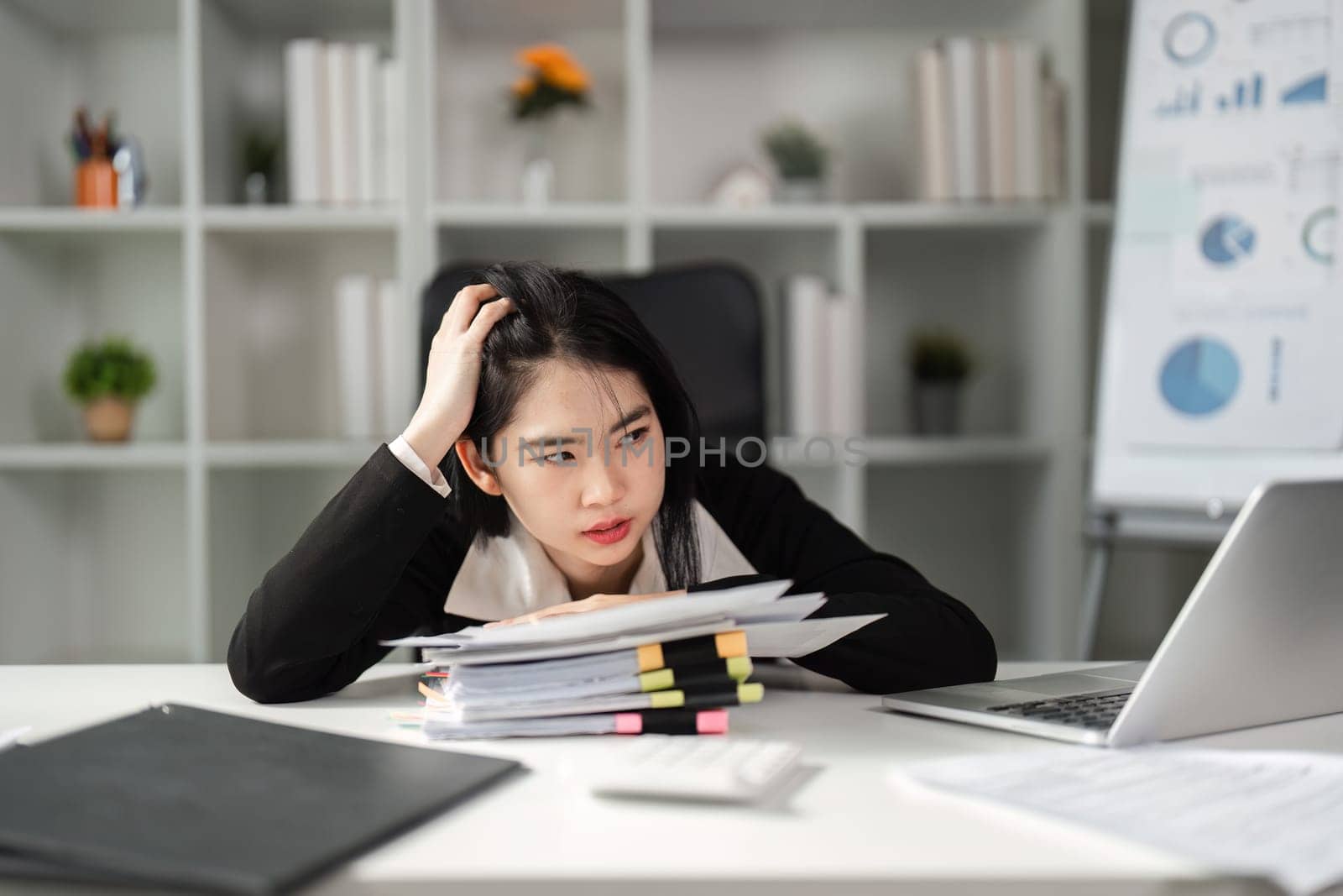 A frustrated businesswoman examines tax paperwork at her desk, facing the pressures of financial management.