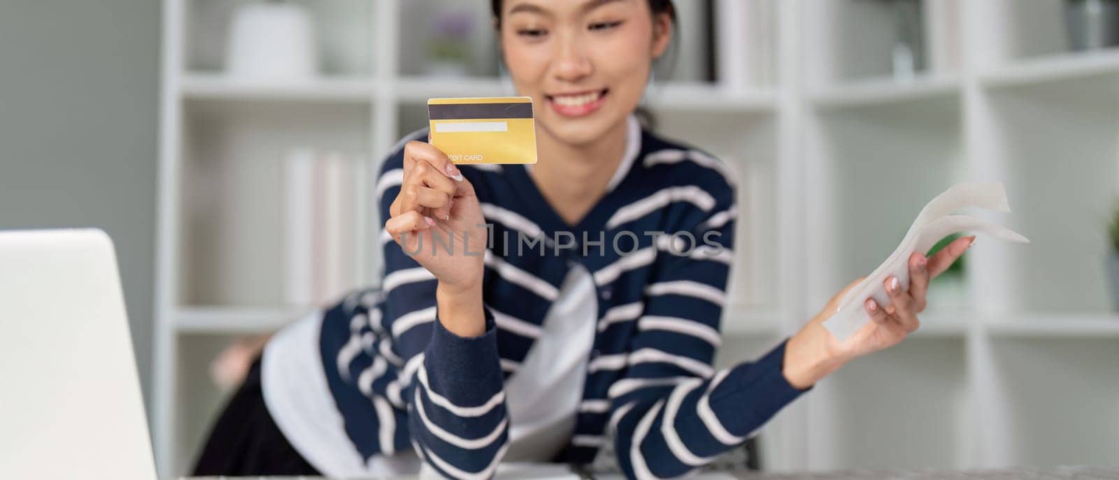A cheerful woman displays her credit card and a bill, symbolizing financial empowerment.