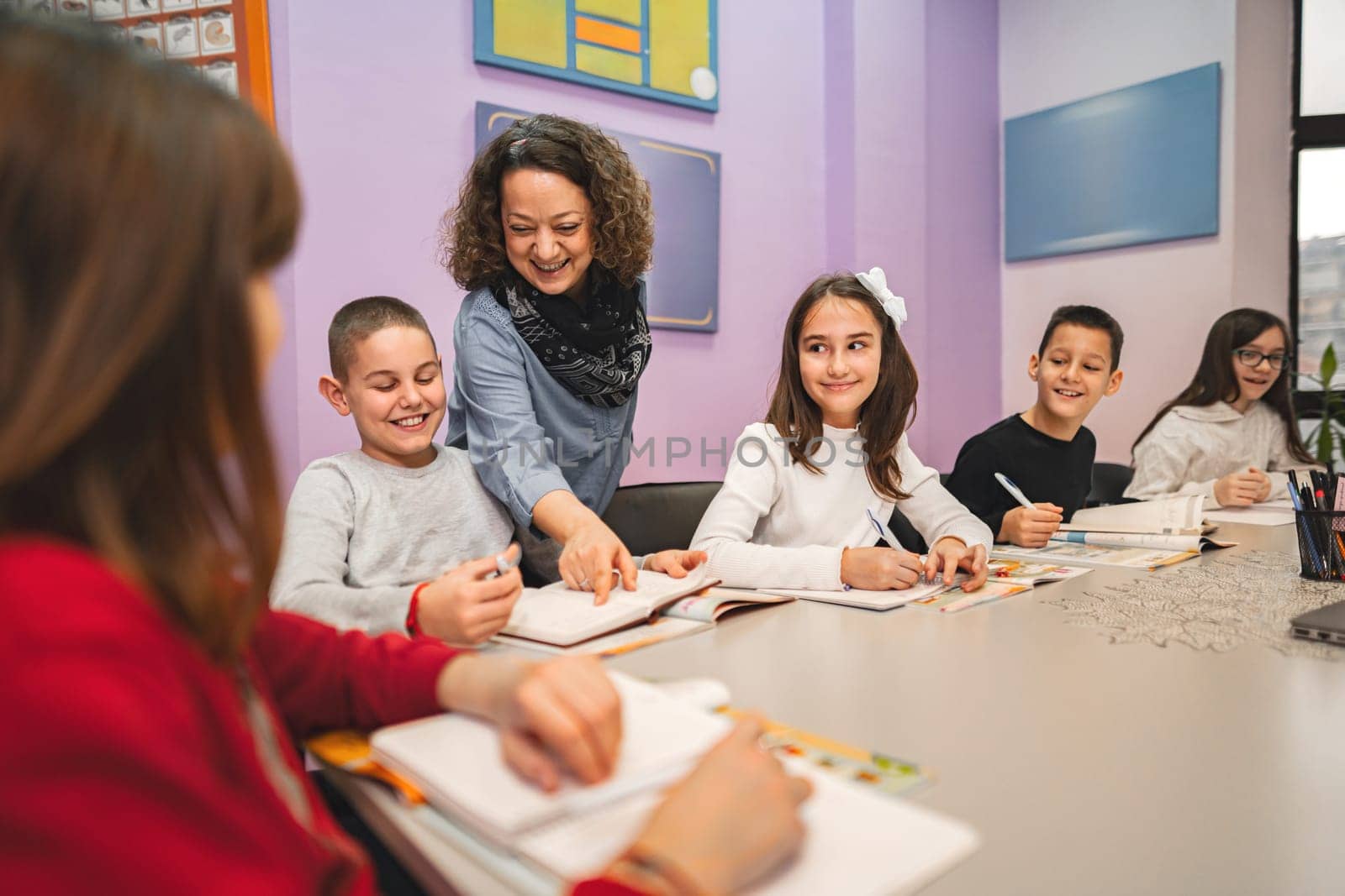 Female teacher helping elementary students at language school class.