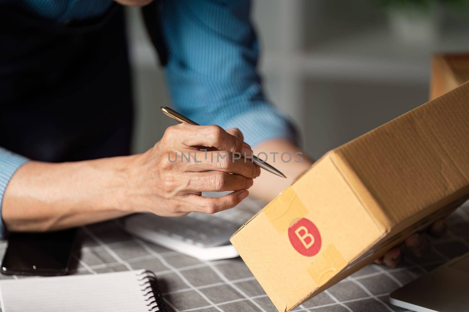 A focused individual labels a package with a pen, showcasing attention to detail in a business setting.