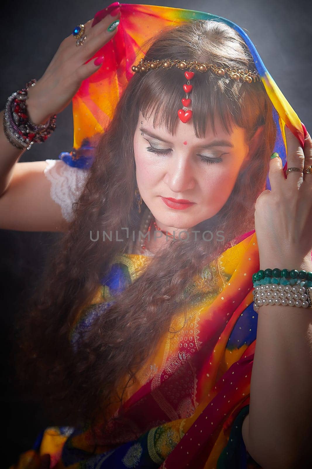 A mature blogger showcases a colorful sari, accentuating traditional elegance while posing softly in an artistic Indian-themed photoshoot.