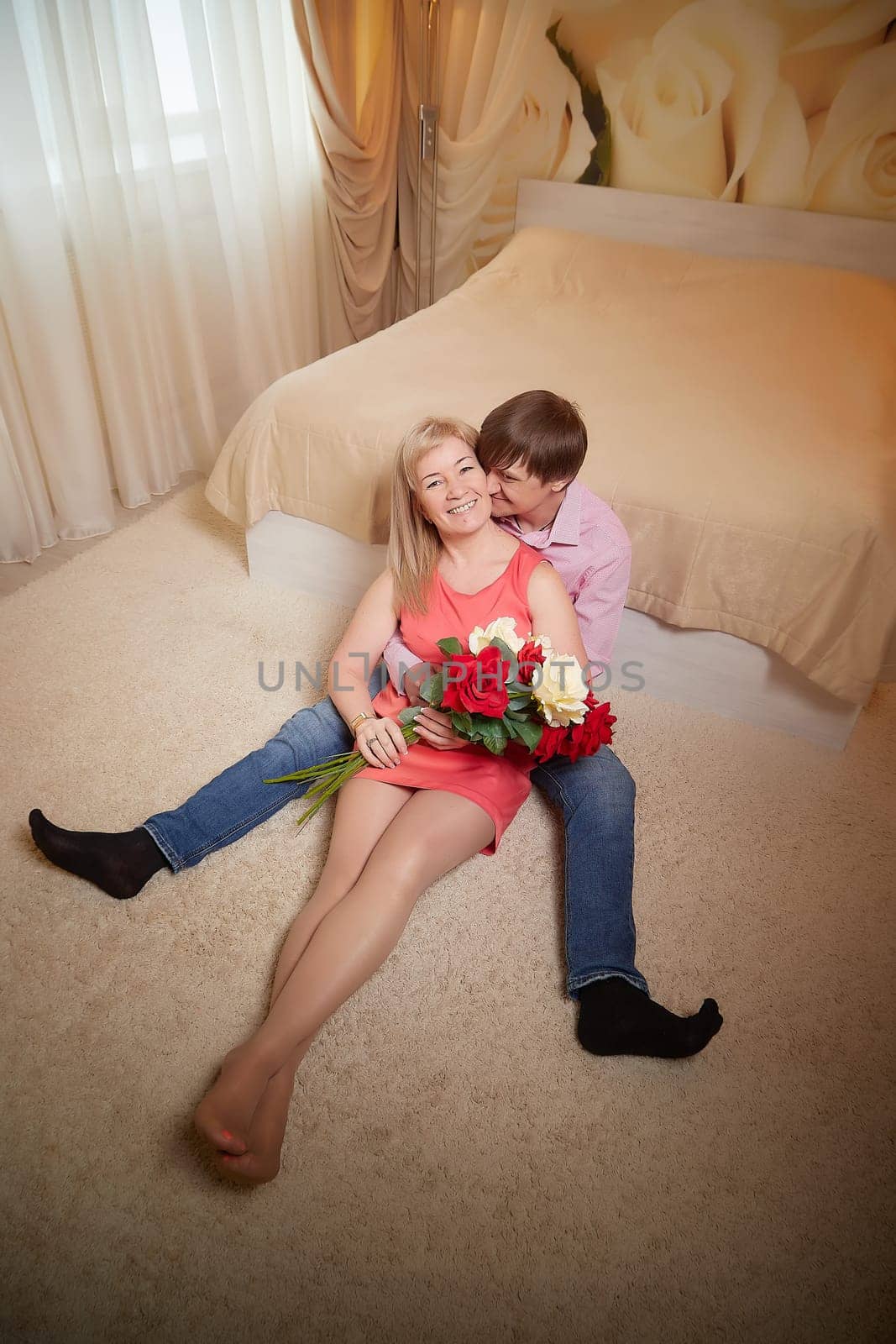 Couple enjoys a romantic moment in a hotel room, surrounded by flowers and celebrating their love.