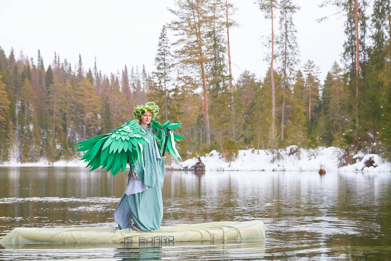 A girl dressed in a flowing green outfit stands on a floating platform on a serene lake, embodying the spirit of spring and nature's beauty.