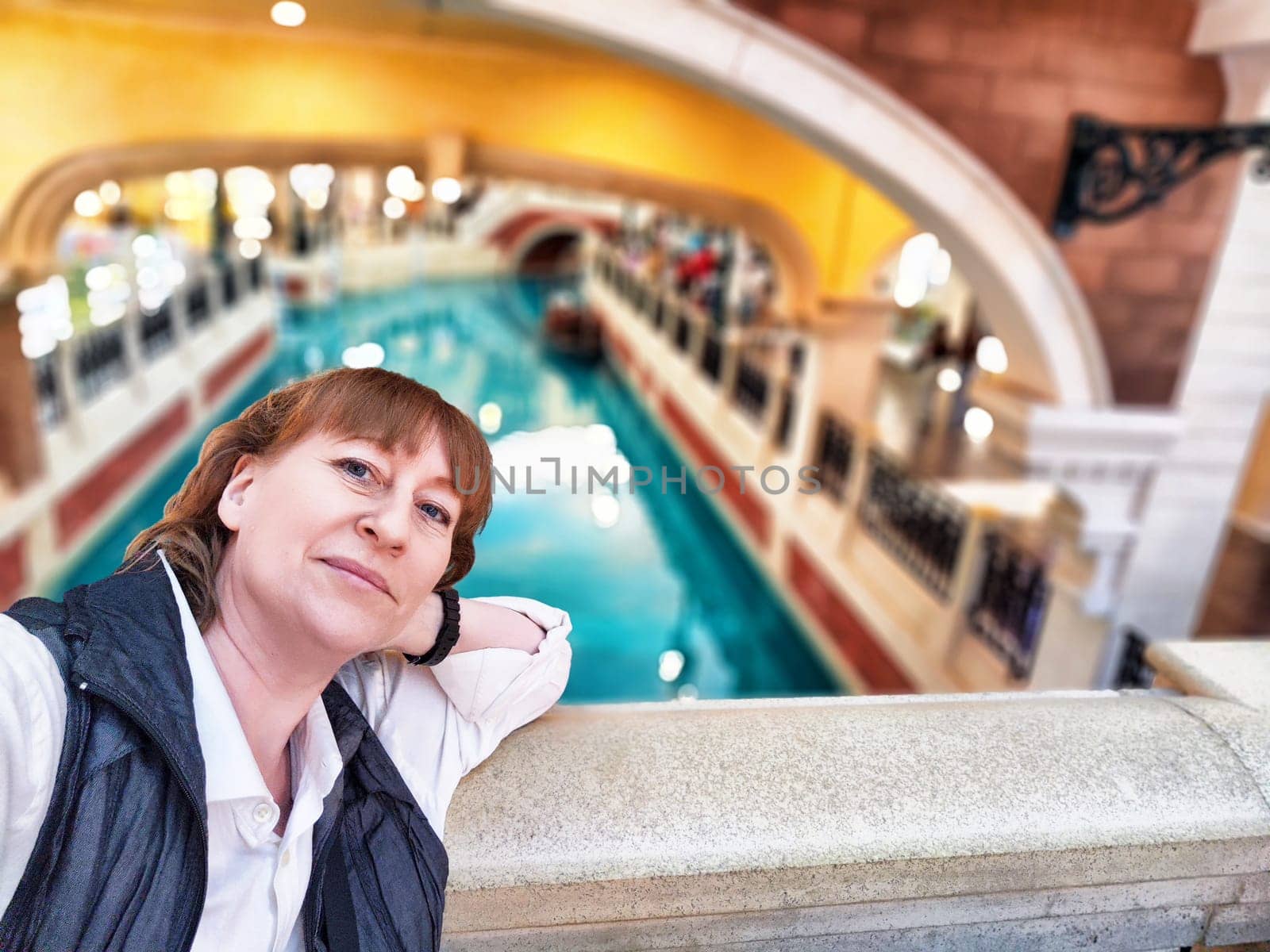 A traveler leans on the railing, taking in the colorful canals of Macau while experiencing the lively entertainment.