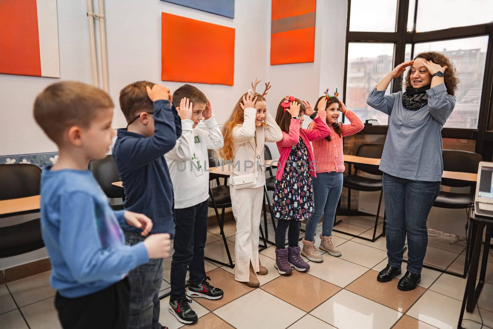 Woman teaching a group of elementary students body parts at language school.