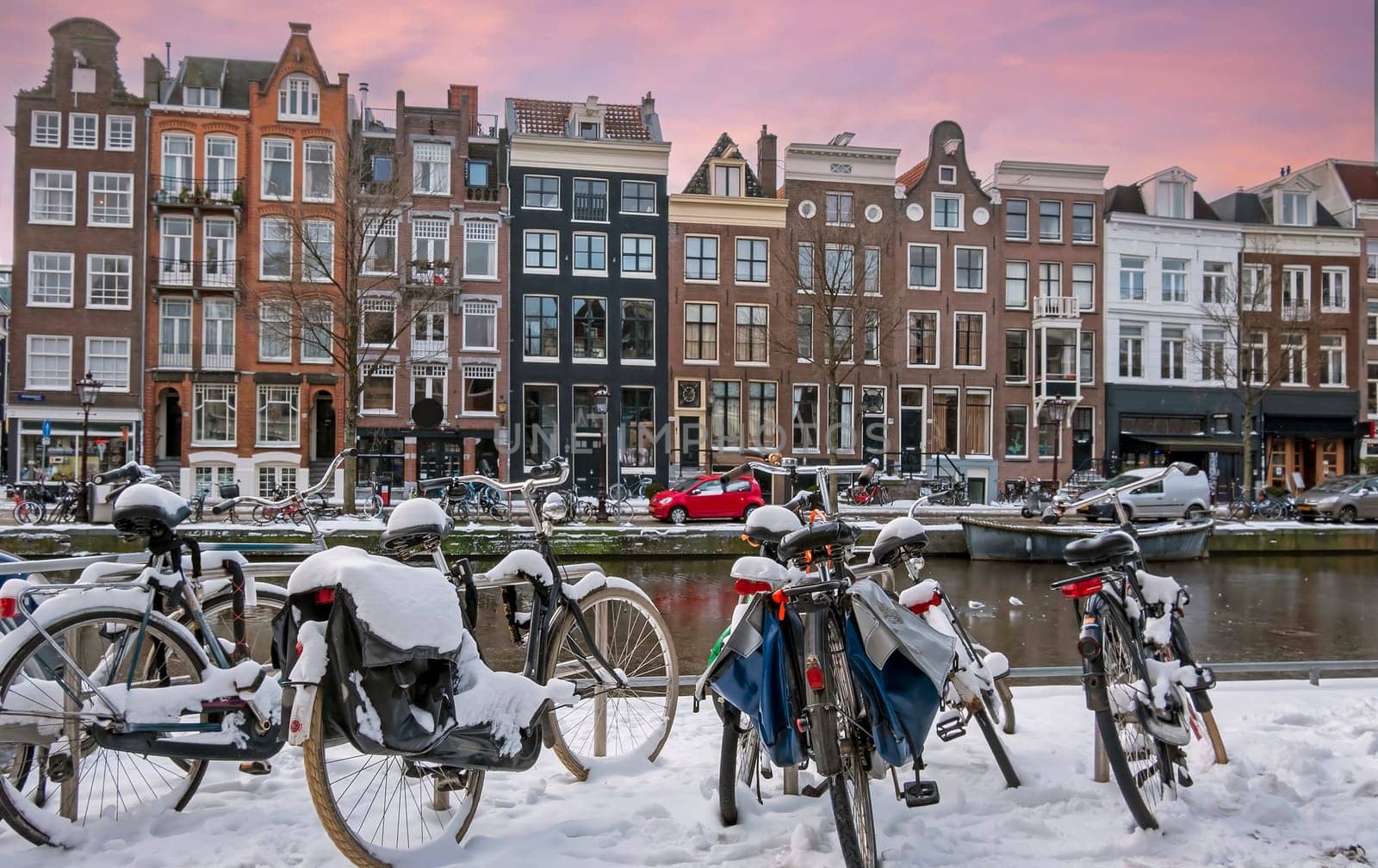 Snowy bikes in Amsterdam in winter in the Netherlands at sunset