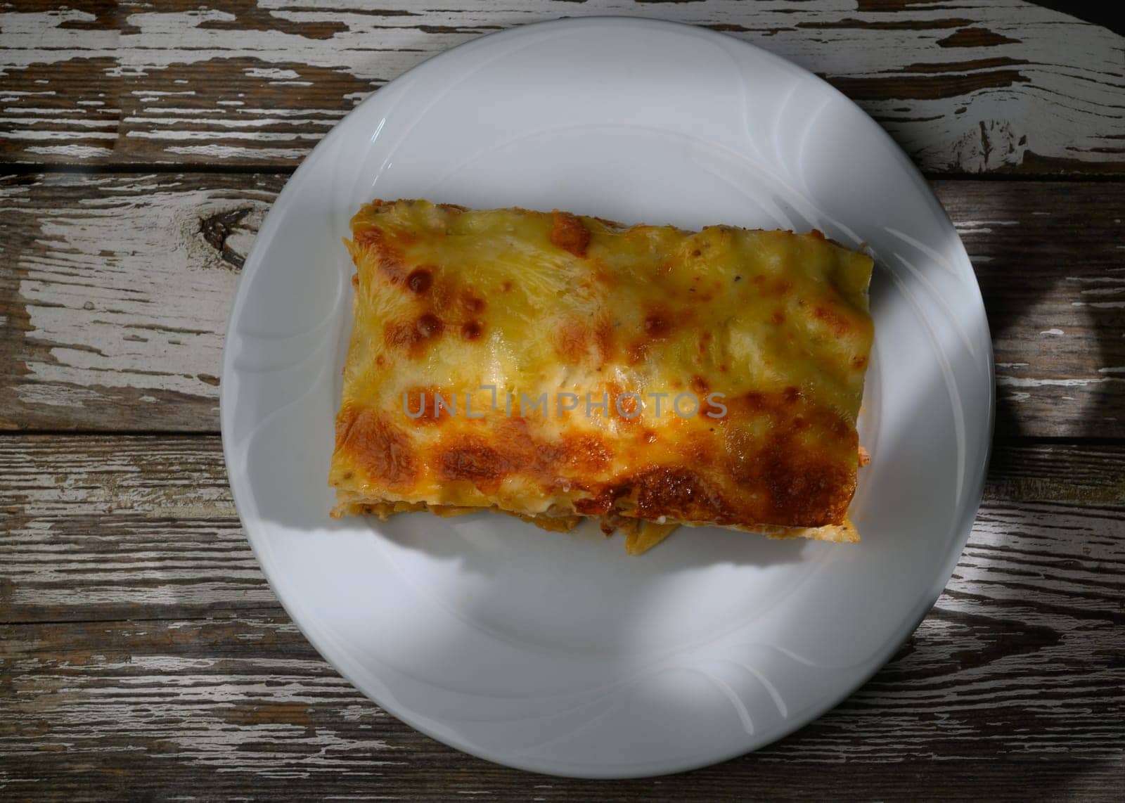 Delicious layers of pasta and cheese await, glowing under soft sunlight on a rustic wooden table setting.