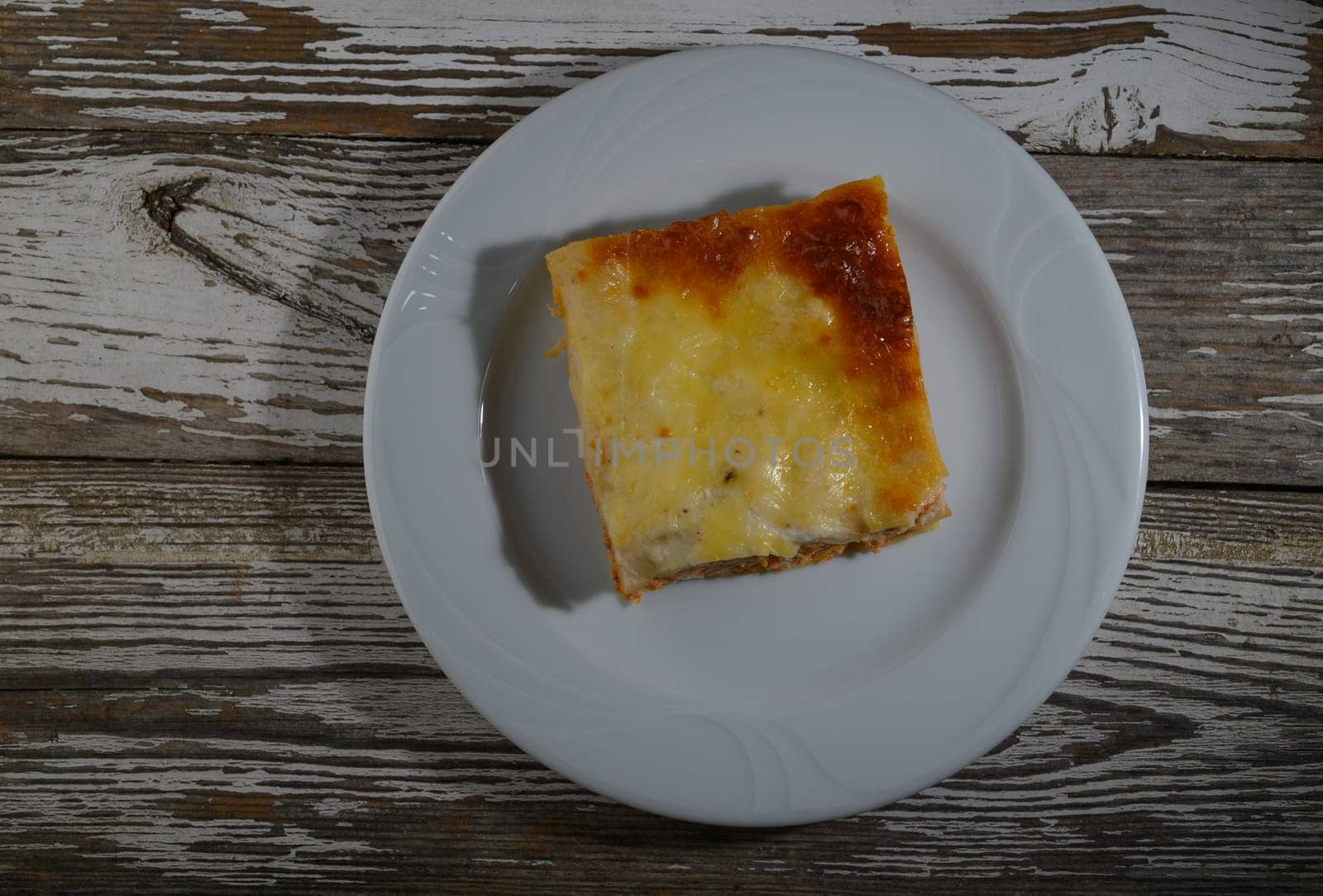 A delectable square of baked casserole sits on a white plate, inviting for a warm meal at dinner time.