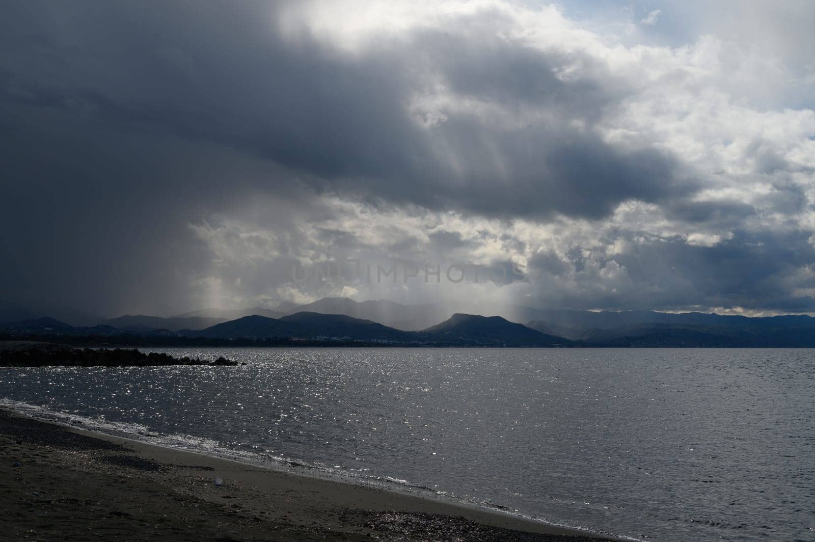 Dramatic skies loom over a serene lake with rippling waters reflecting light, creating a striking evening atmosphere.