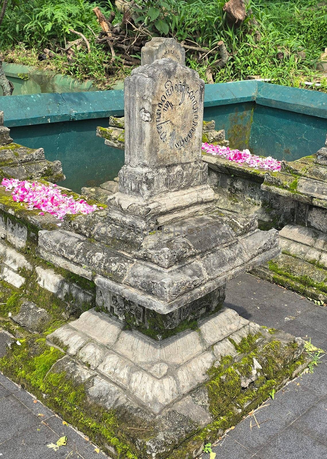 Ancient ancestors javanese king and queen burial in remote jawa, Indonesia, traditional moss-covered stone graves decorated with pink flower petals, depicting respect and cultural heritage in a serene environment surrounded by greenery