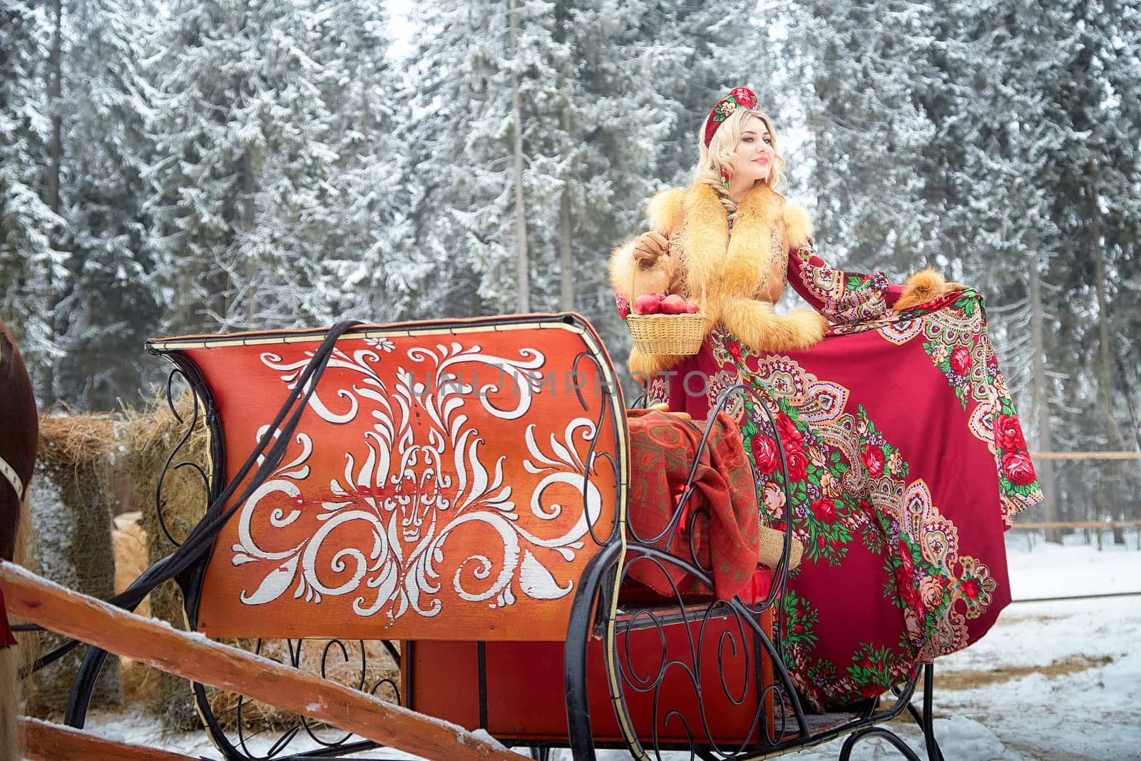 A girl in traditional Russian dress interacts with a horse during the winter Maslenitsa celebration.