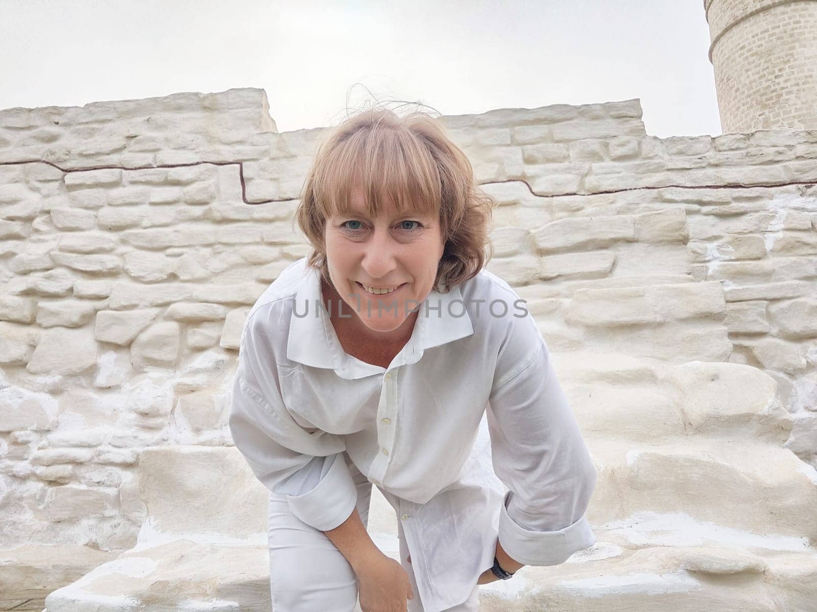 A blonde woman captures a selfie while exploring ancient ruins, showcasing her excitement for travel and adventure as a blogger.