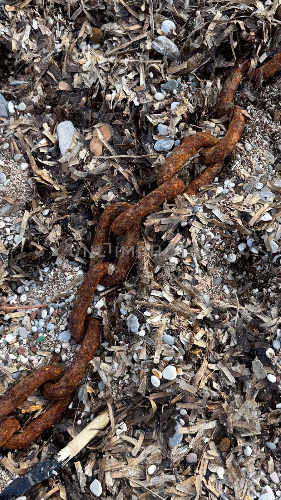 Close-up of large links of rusty chain on pebble beach after storm. High quality photos.