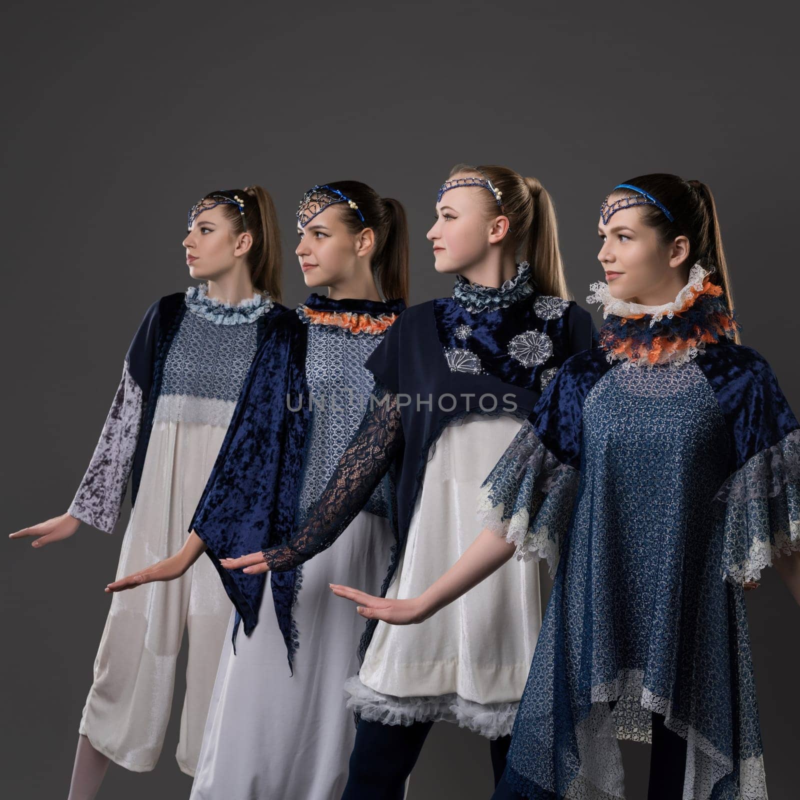 Four dancers dressed in stylish outfits pose gracefully, showcasing their synchronized movements in a performance setting.