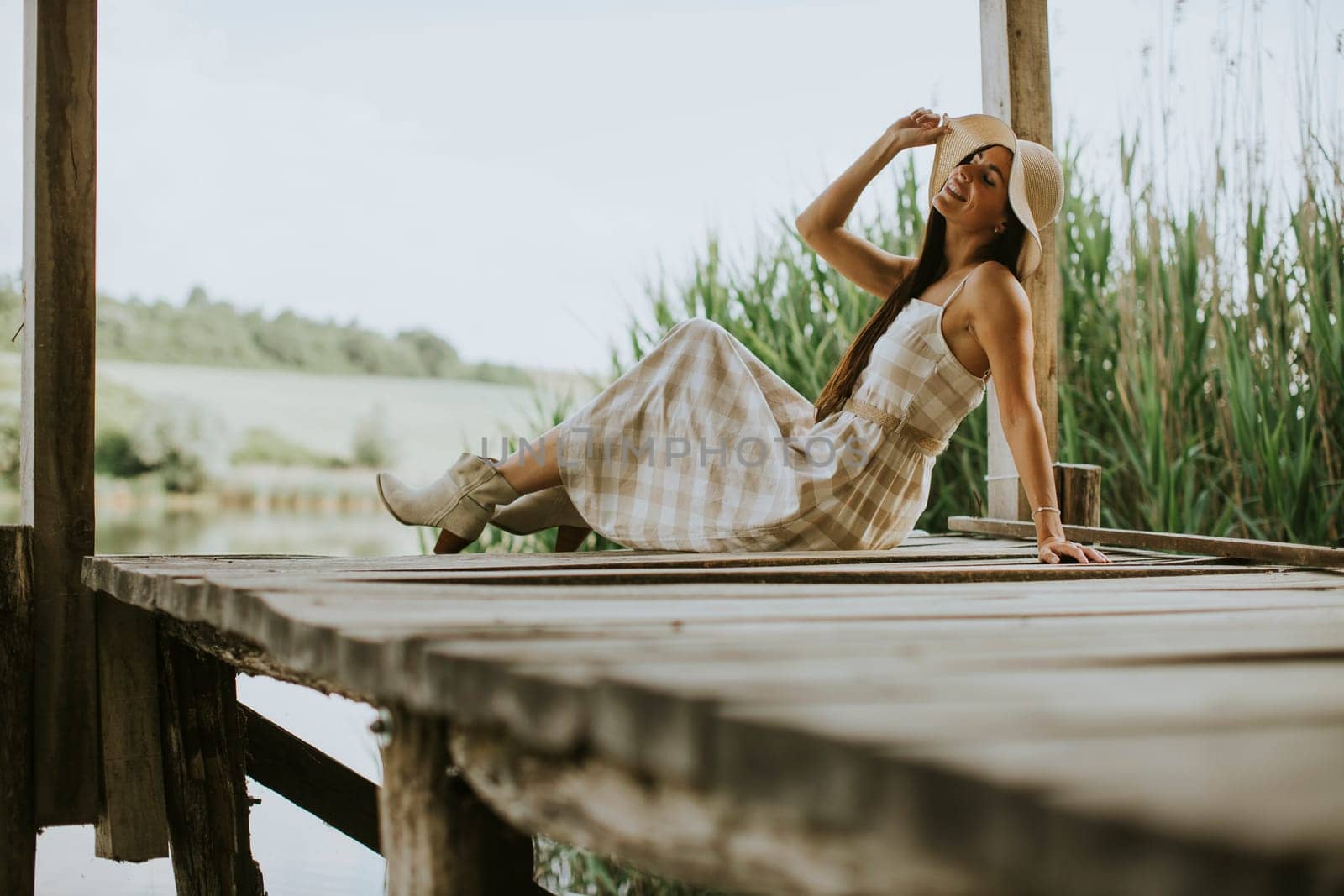 relaxing young woman on wooden pier at the calm lake