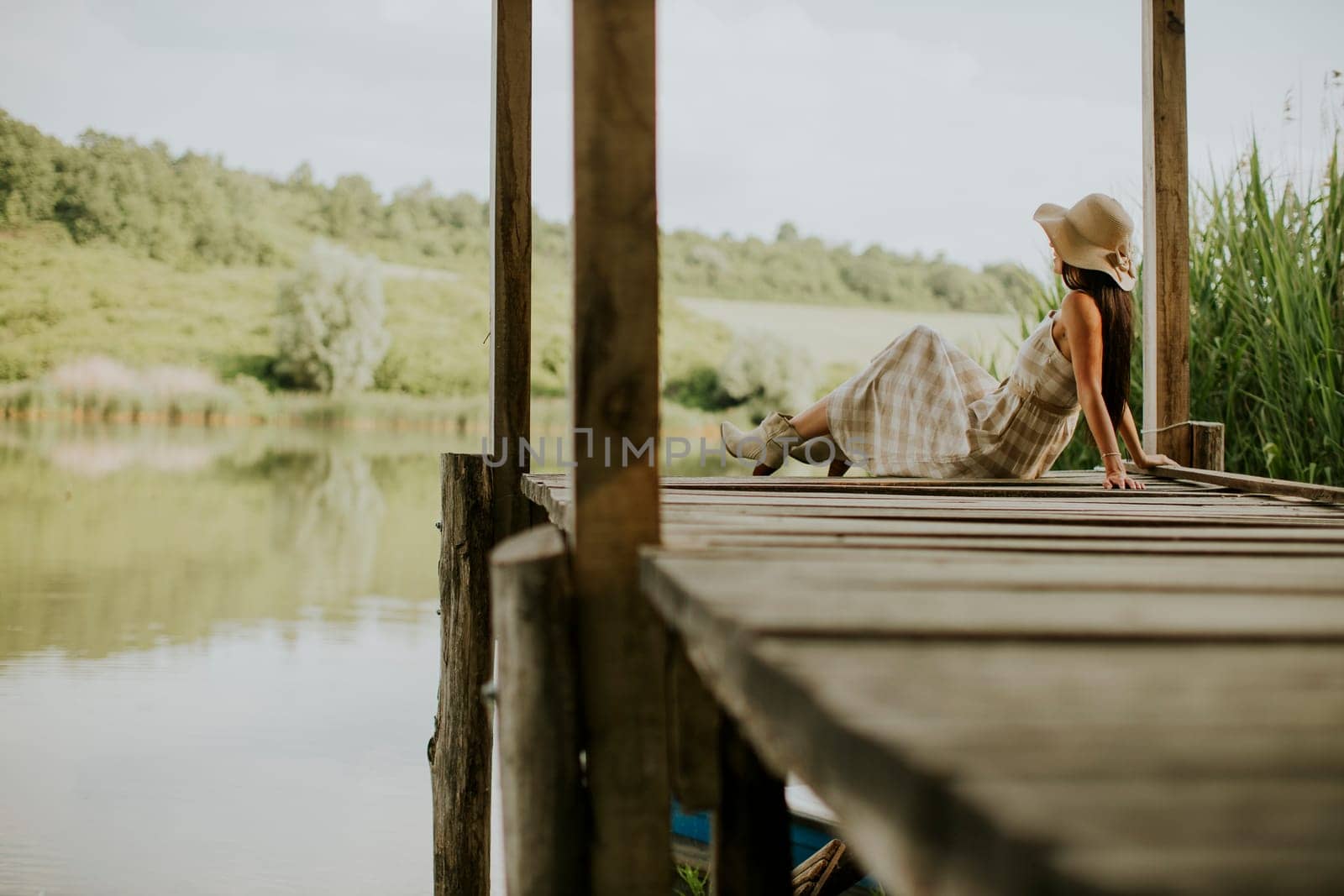 relaxing young woman on wooden pier at the calm lake