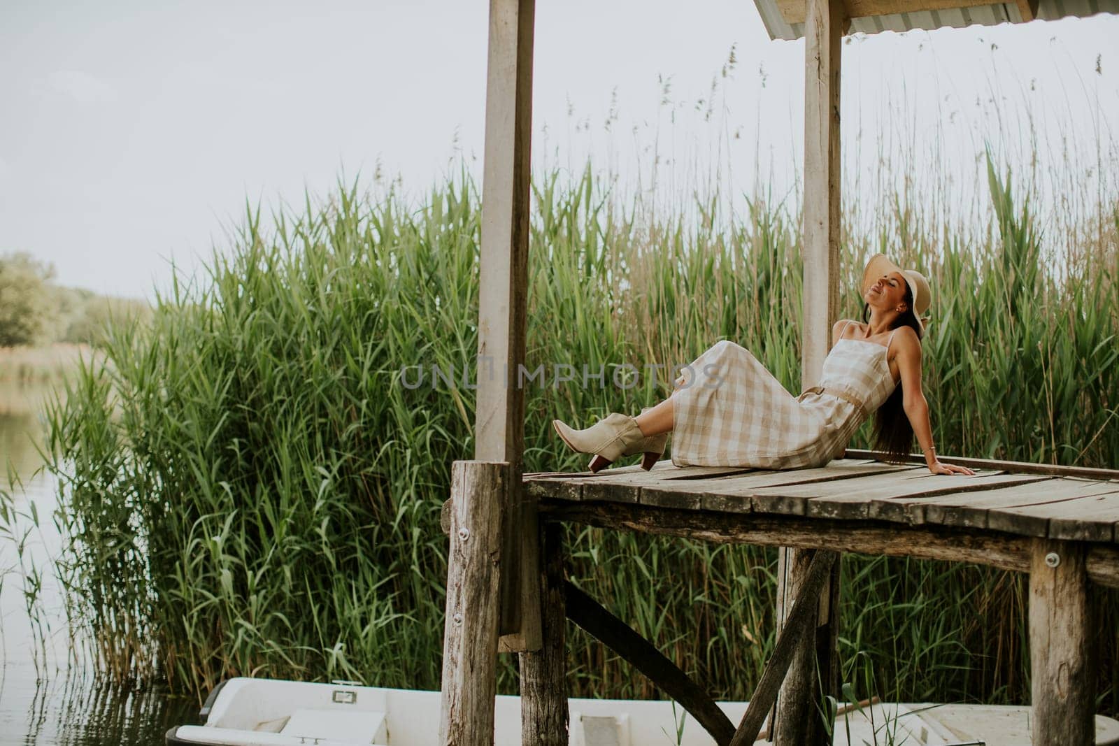 relaxing young woman on wooden pier at the calm lake
