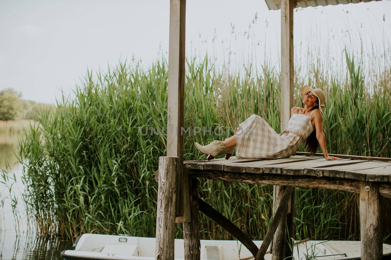 relaxing young woman on wooden pier at the calm lake