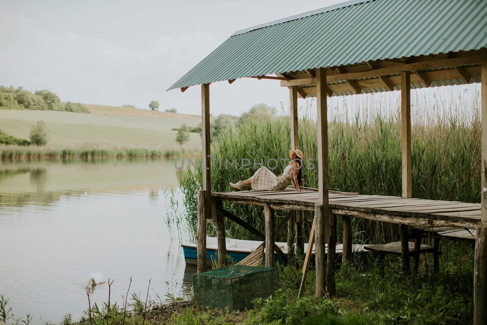 relaxing young woman on wooden pier at the calm lake