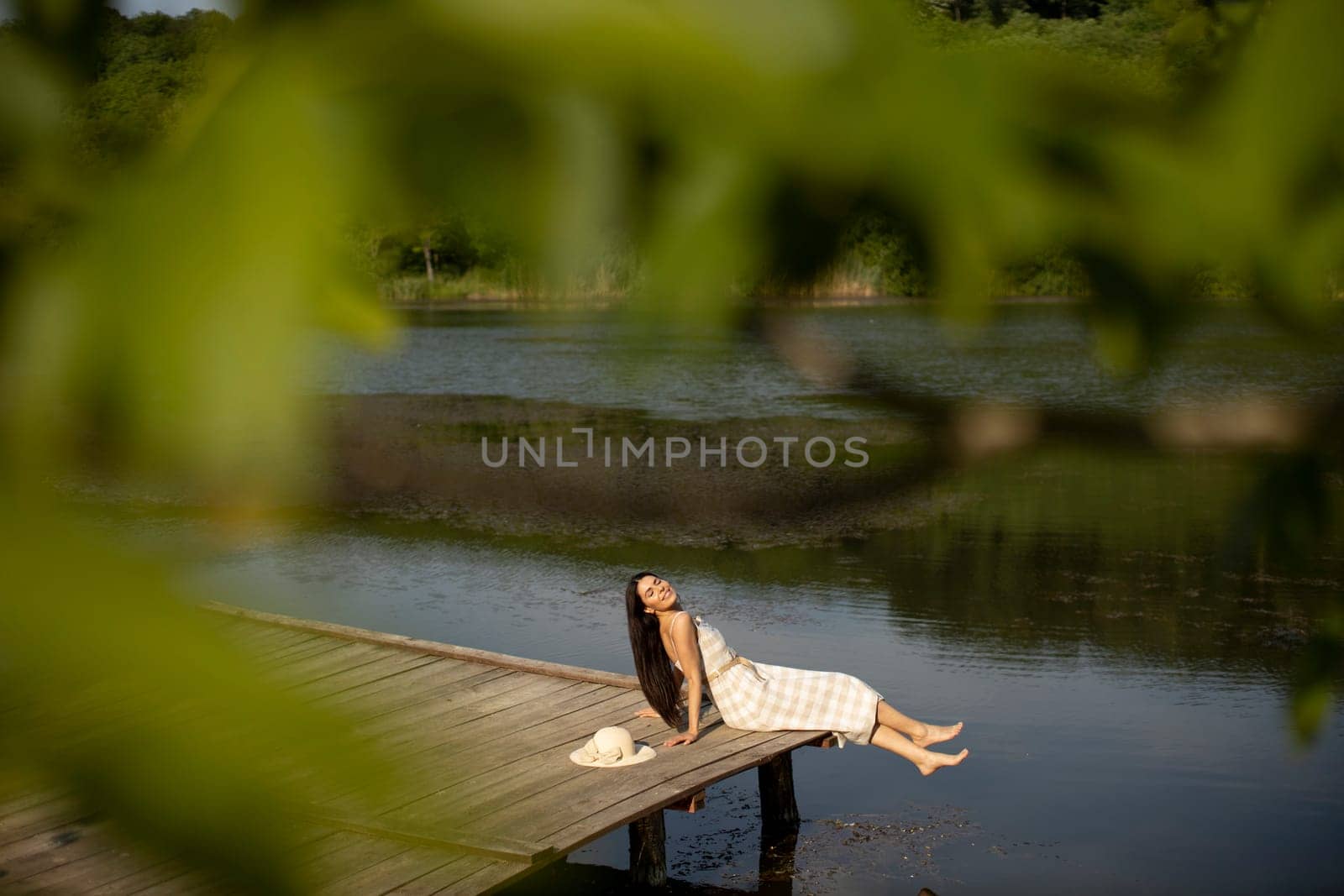 relaxing young woman on wooden pier at the calm lake