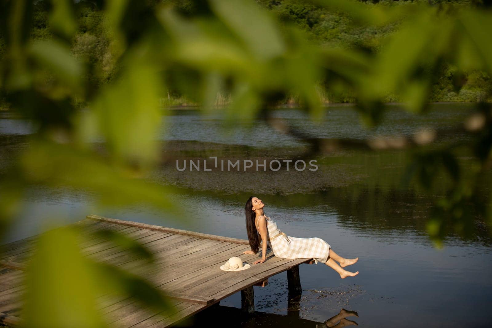 relaxing young woman on wooden pier at the calm lake