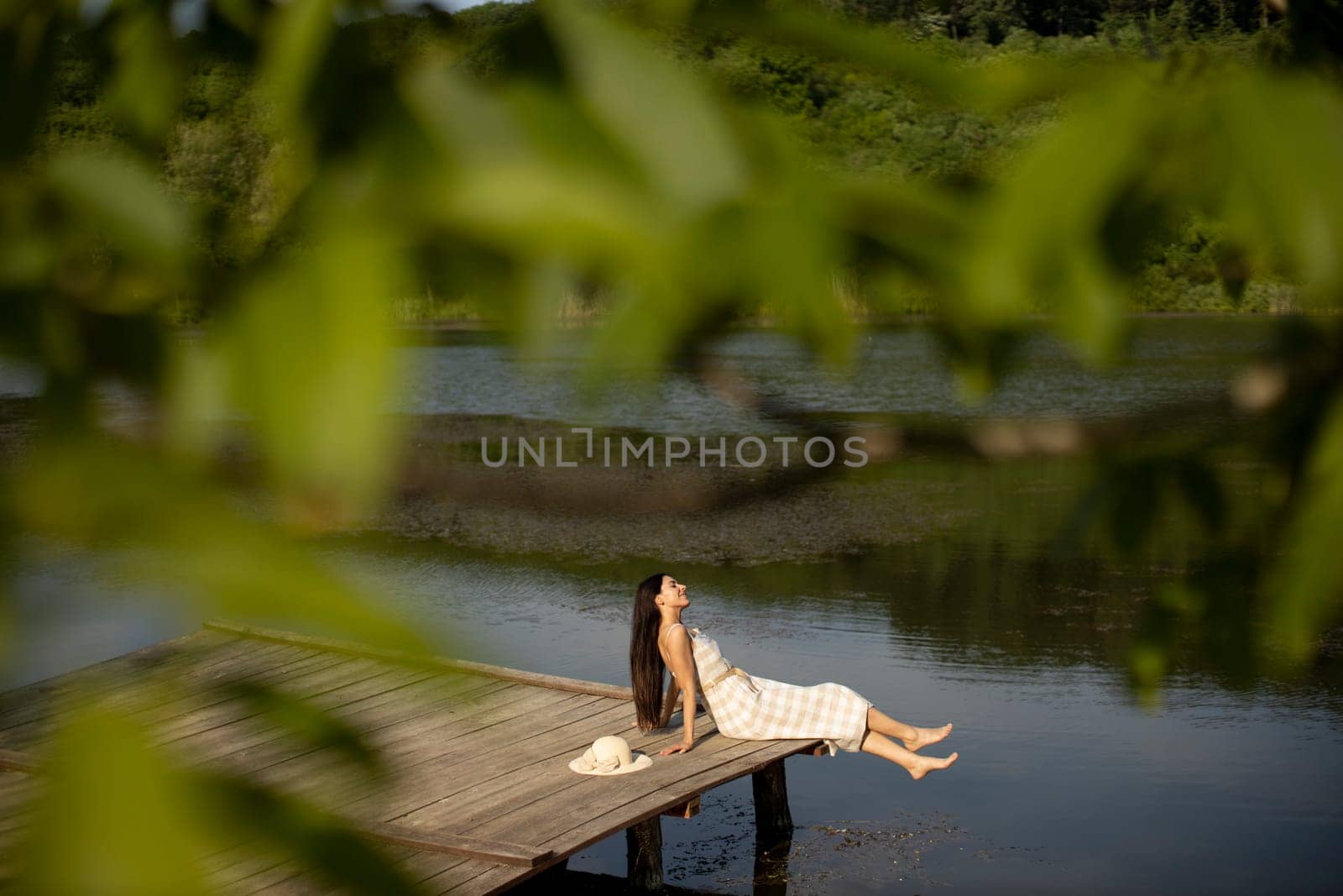 relaxing young woman on wooden pier at the calm lake