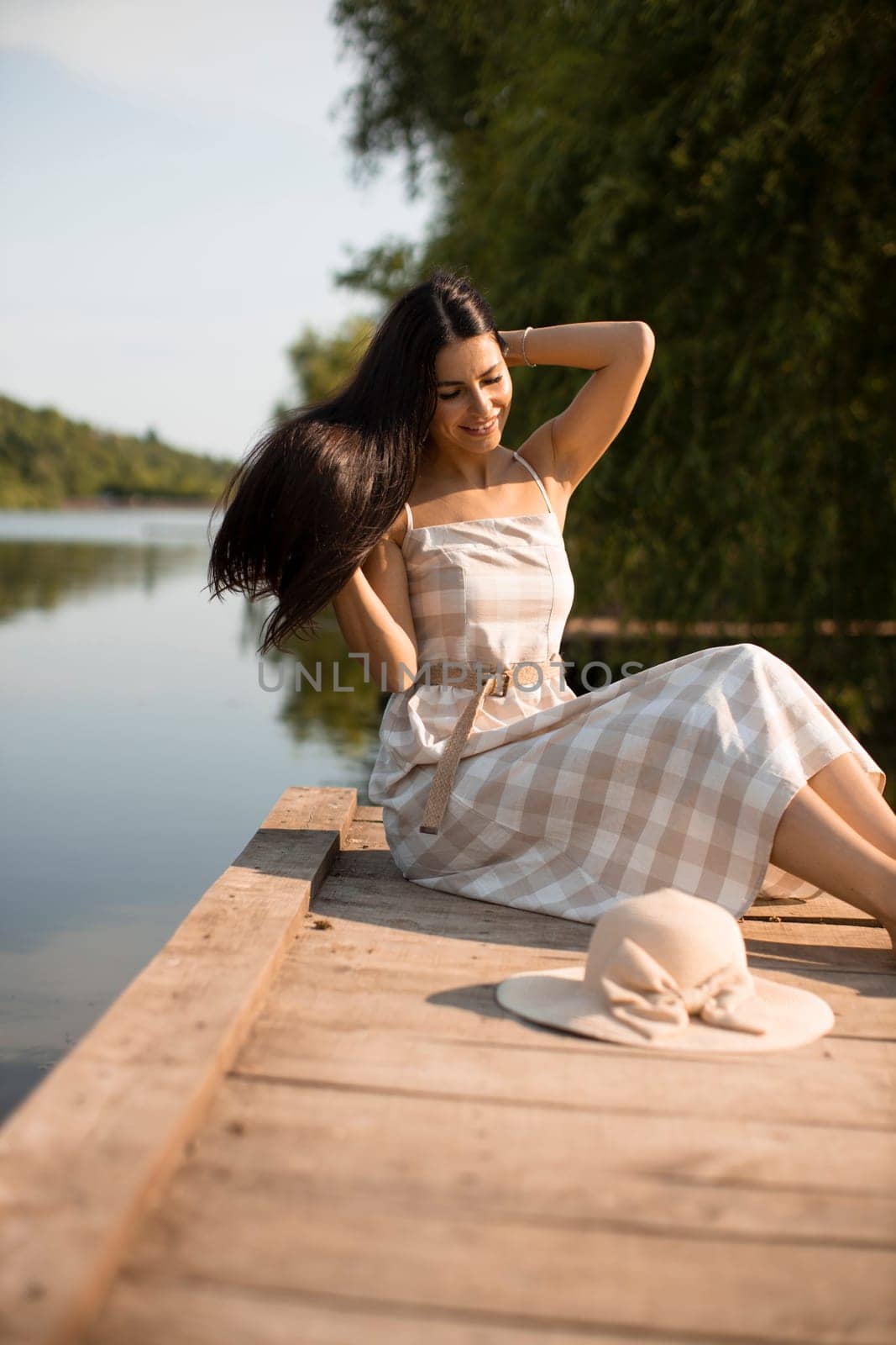 relaxing young woman on wooden pier at the calm lake