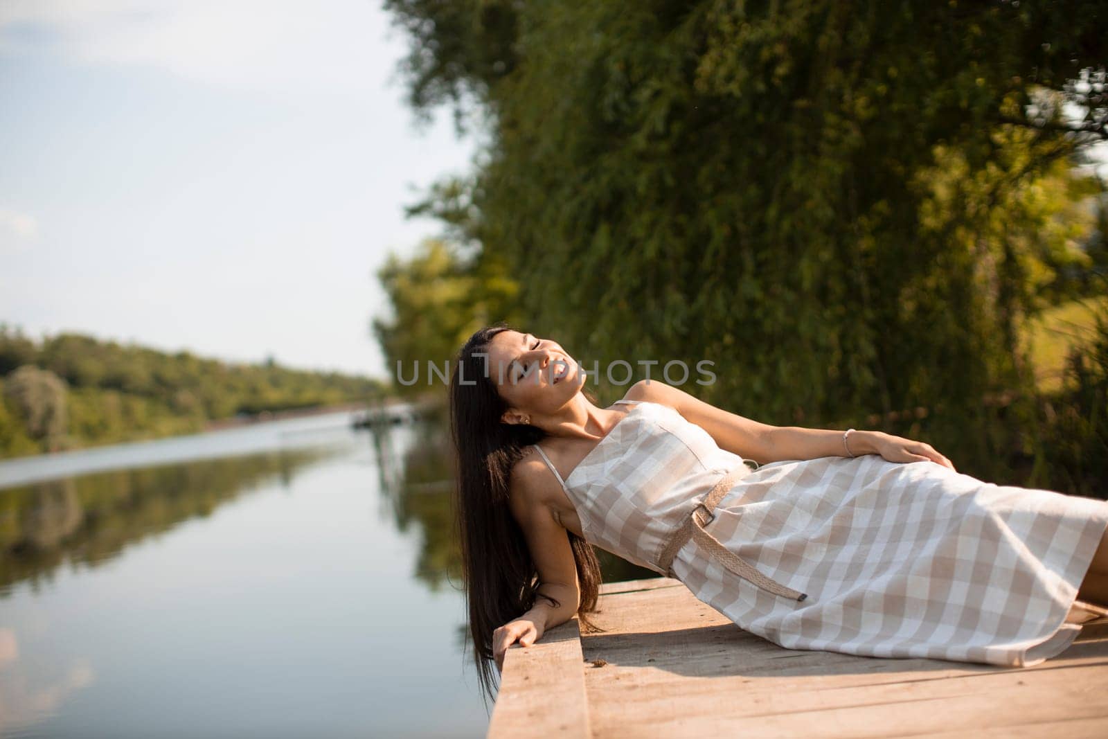 relaxing young woman on wooden pier at the calm lake