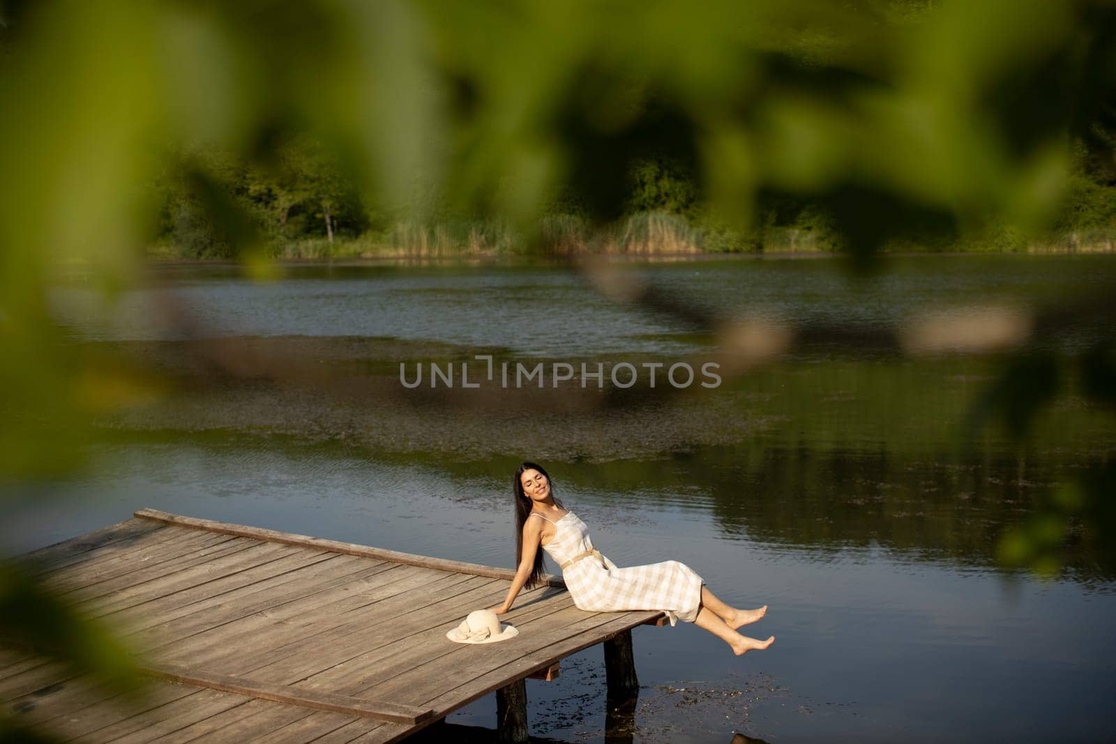 relaxing young woman on wooden pier at the calm lake