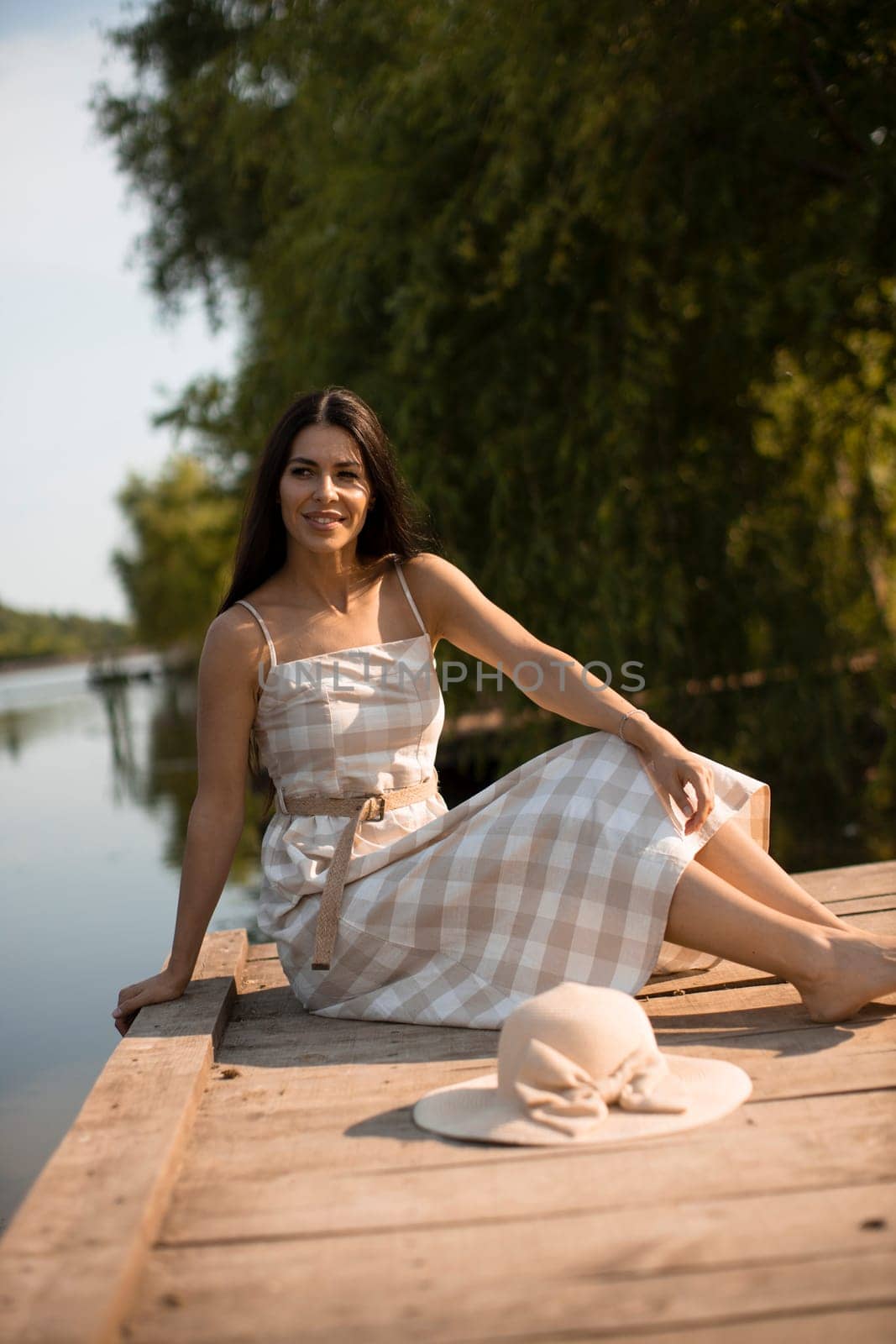 relaxing young woman on wooden pier at the calm lake