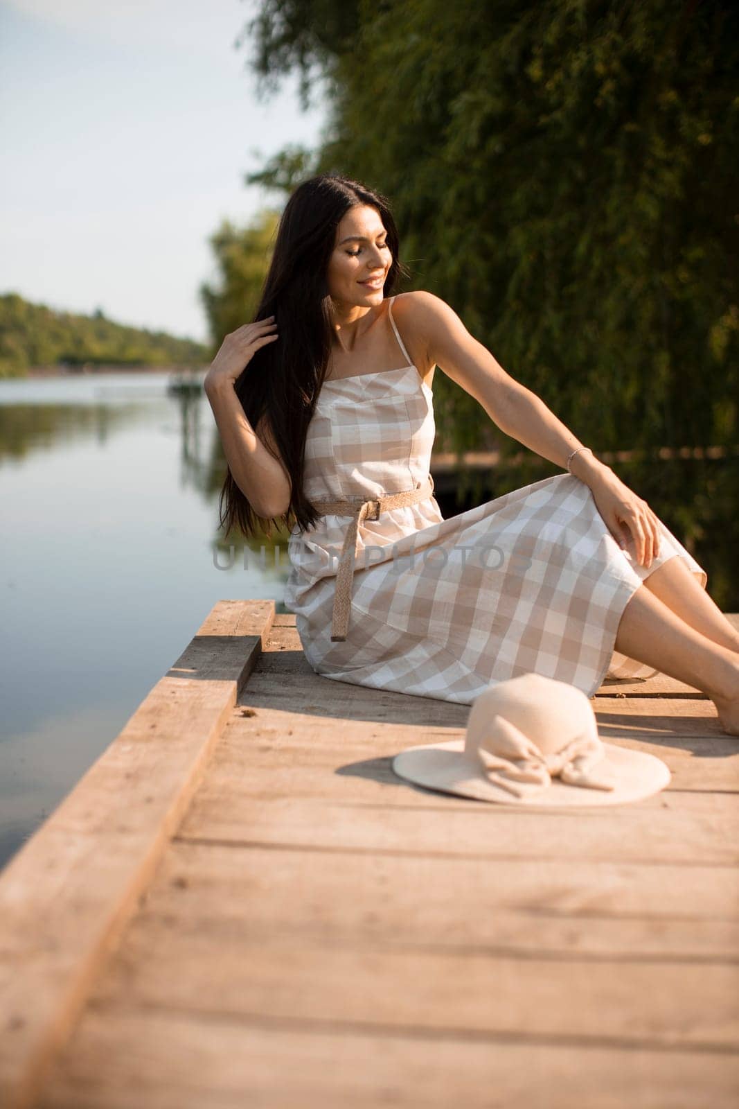 relaxing young woman on wooden pier at the calm lake