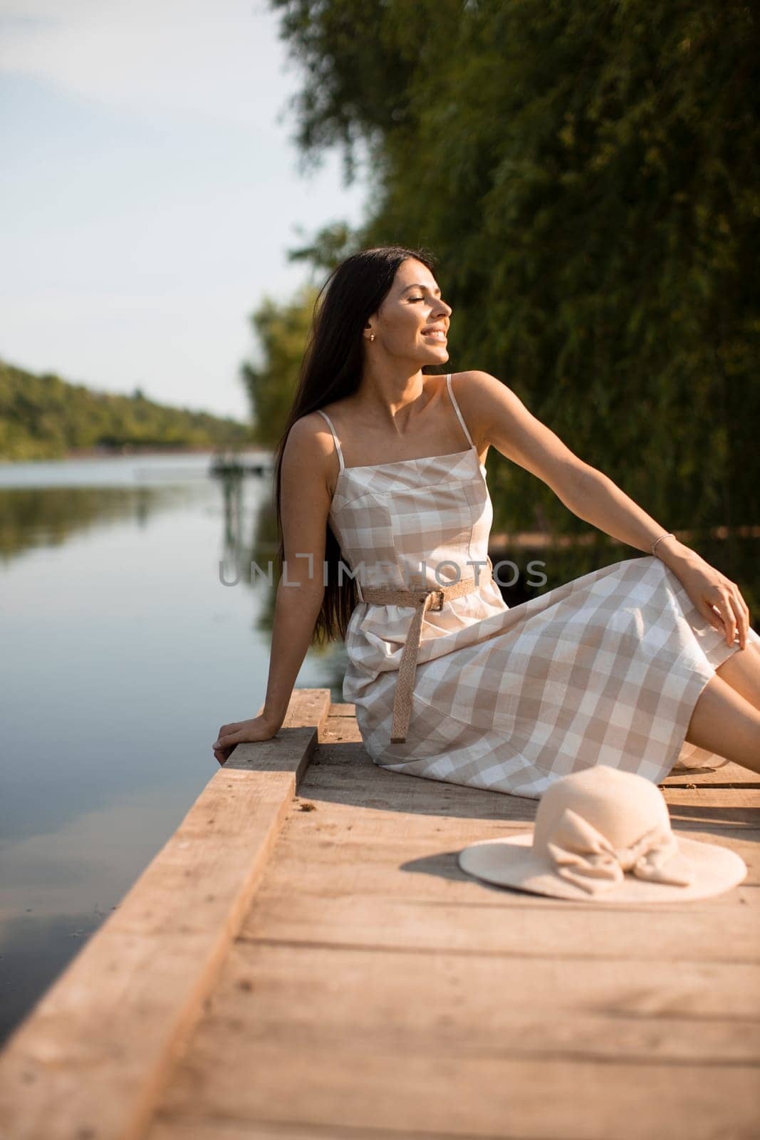 relaxing young woman on wooden pier at the calm lake