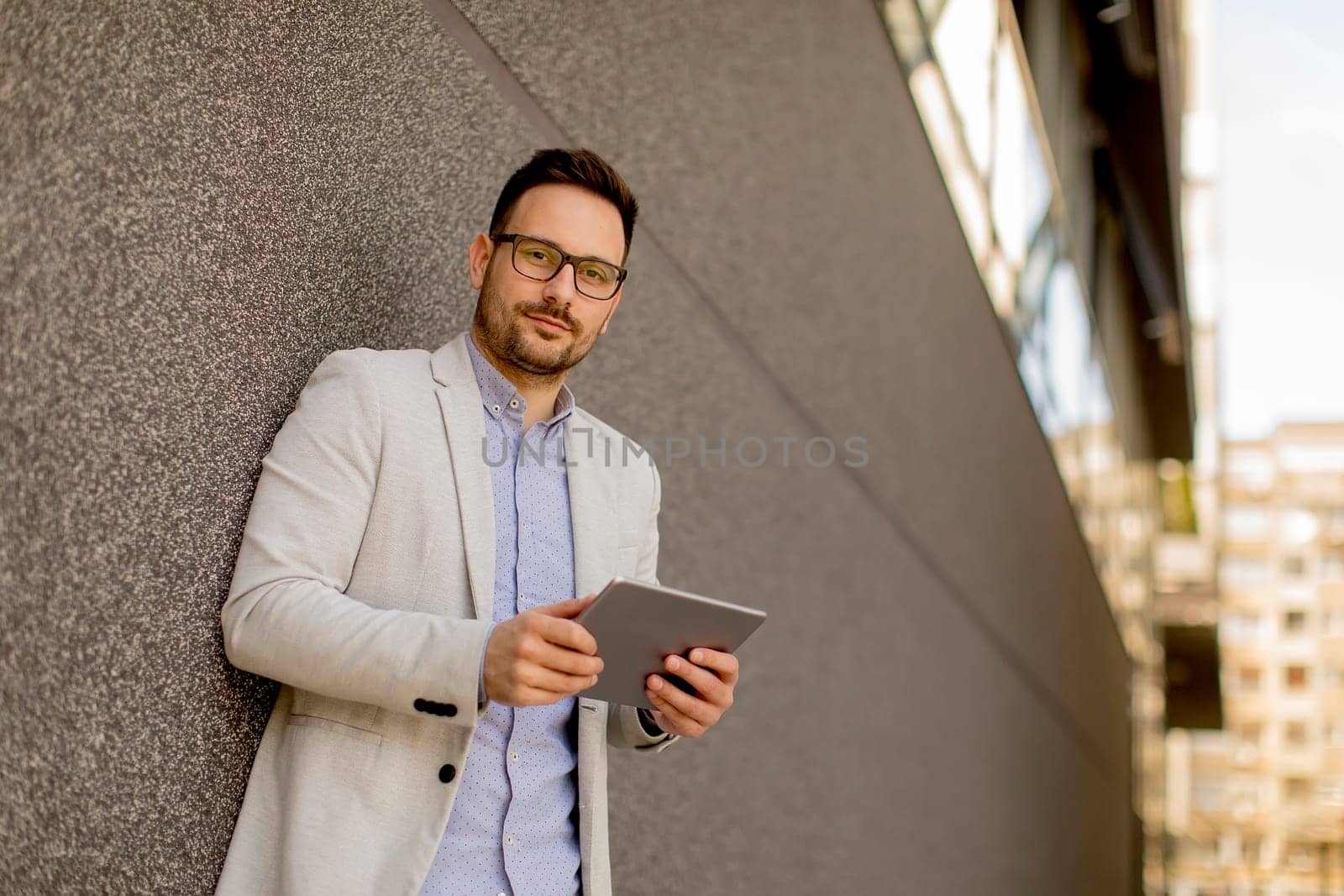 Portrait of young businessman with digital tablet standing outdoor