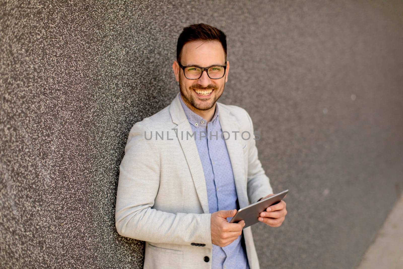 Portrait of a young businessman holding digital tablet outdoor in urban enviroment