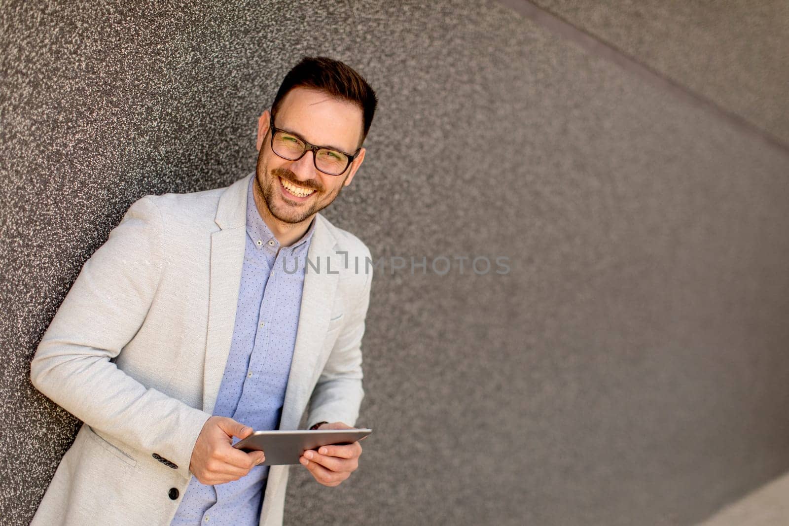 Portrait of a young businessman holding digital tablet outdoor in urban enviroment