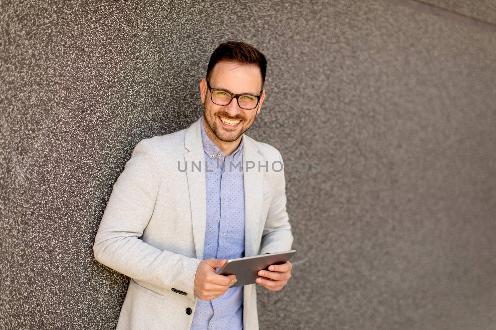 Portrait of a young businessman holding digital tablet outdoor in urban enviroment