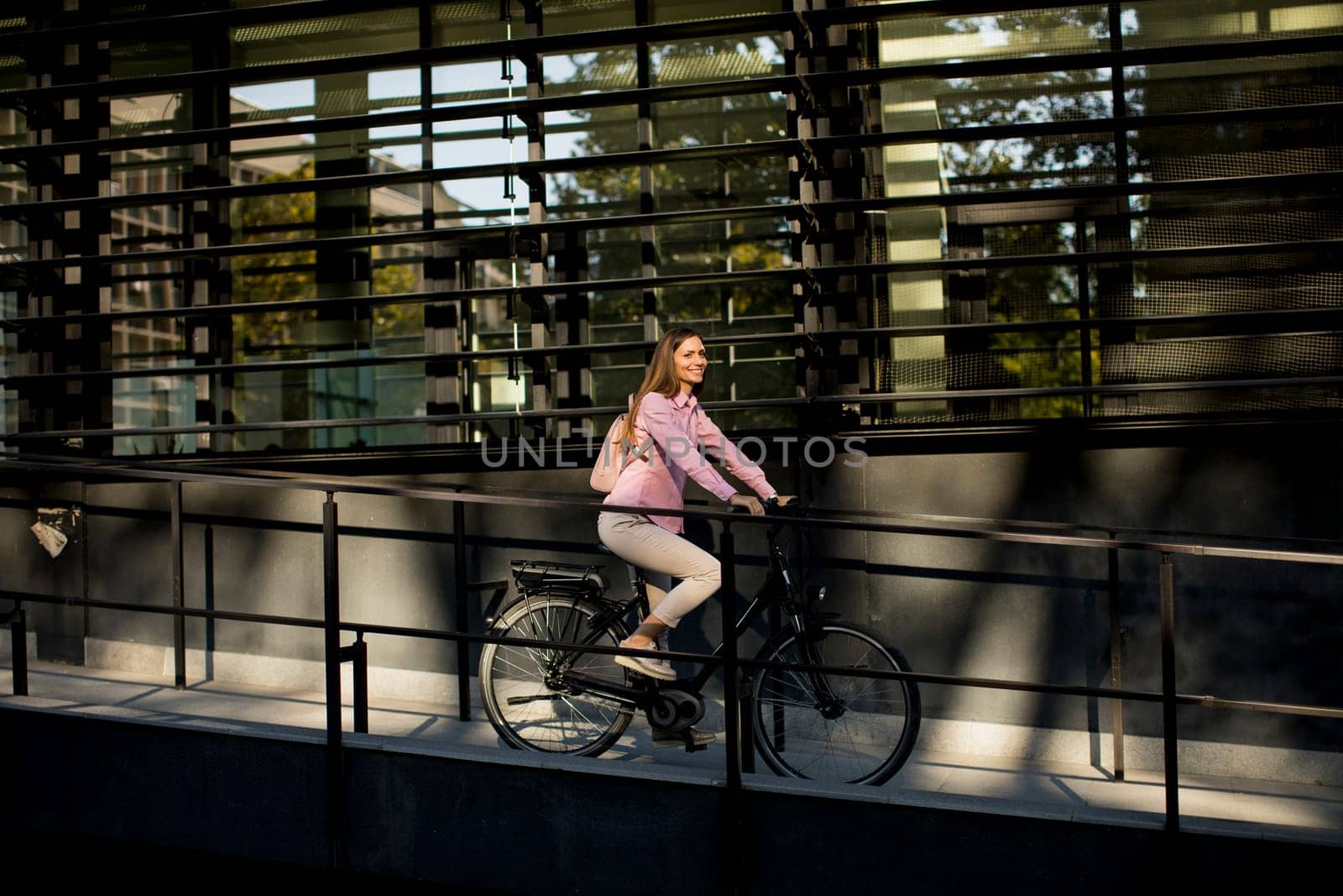 Young woman riding e bike in urban enviroment at sunny day
