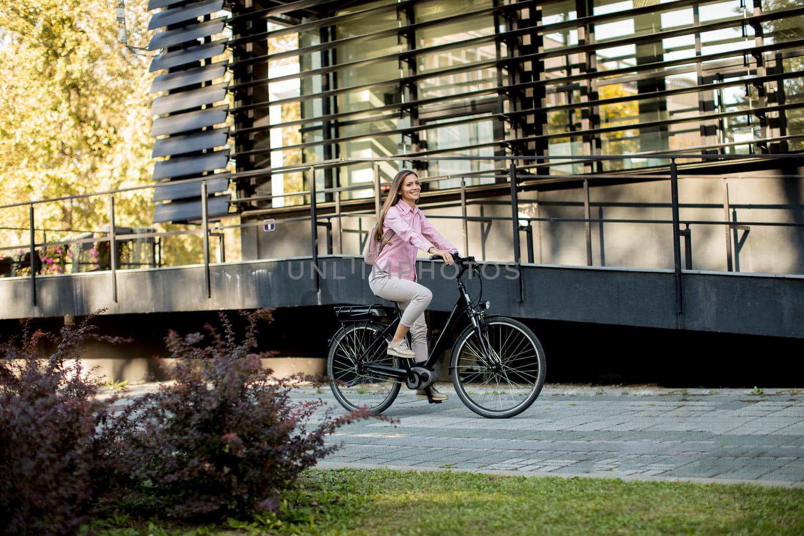 Young woman riding e bike in urban enviroment at sunny day