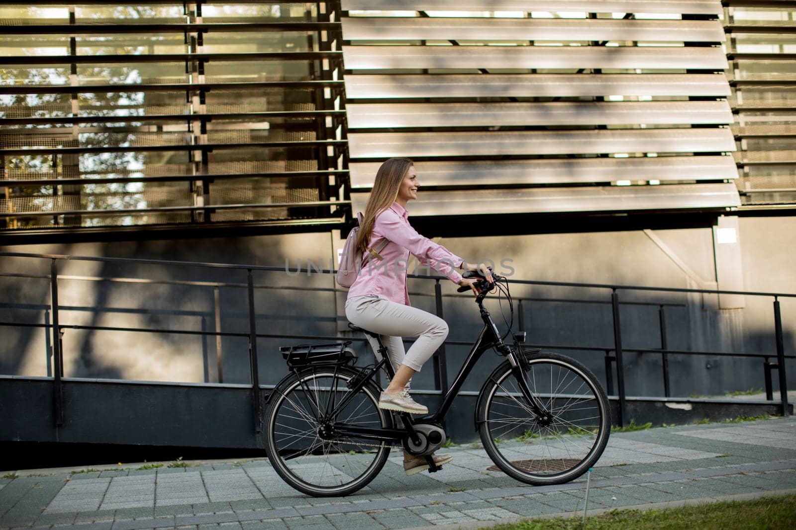 Young woman riding e bike in urban enviroment at sunny day