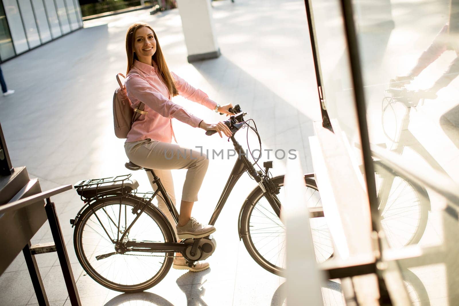 Young woman riding e bike in urban enviroment at sunny day