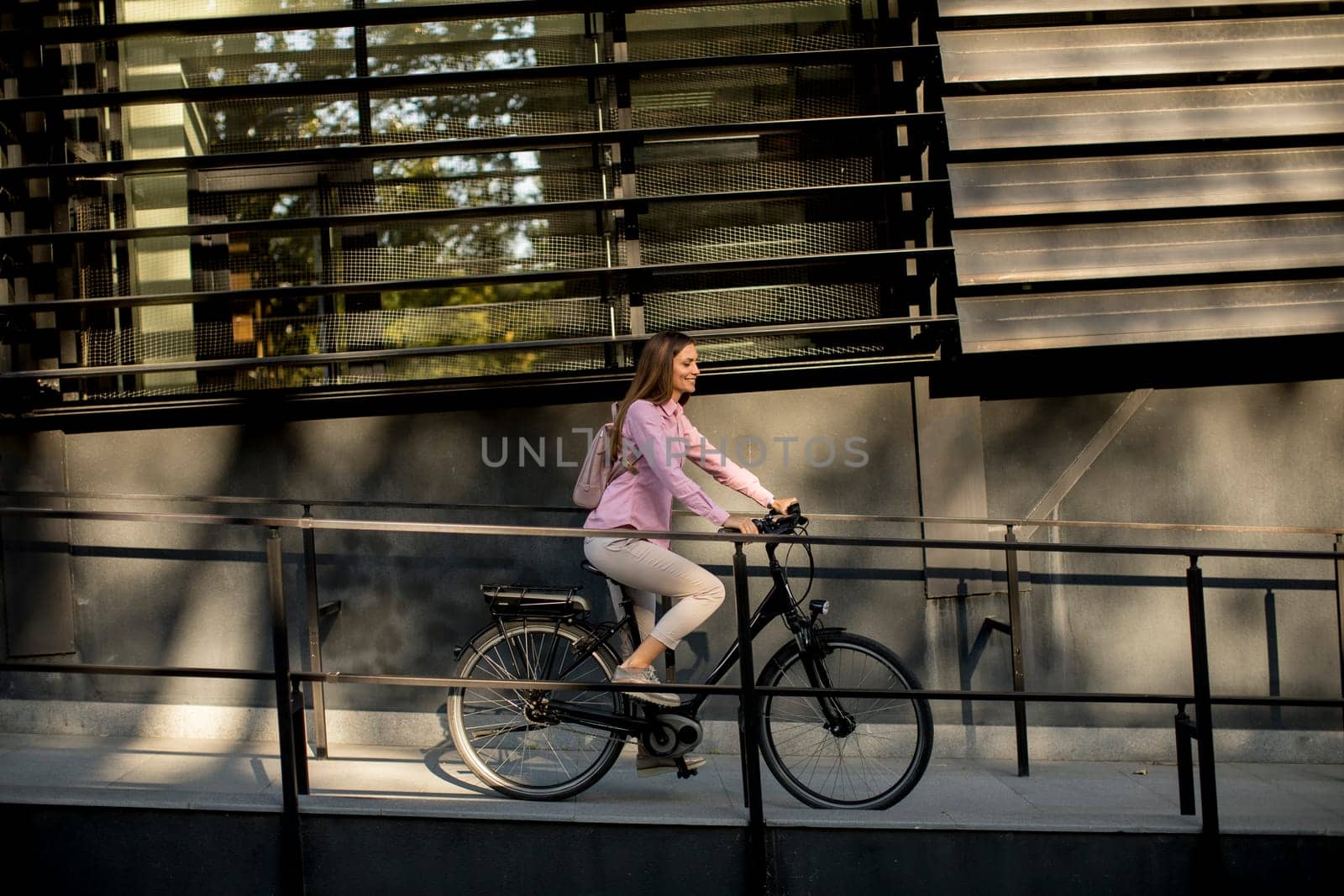 Young woman riding e bike in urban enviroment at sunny day