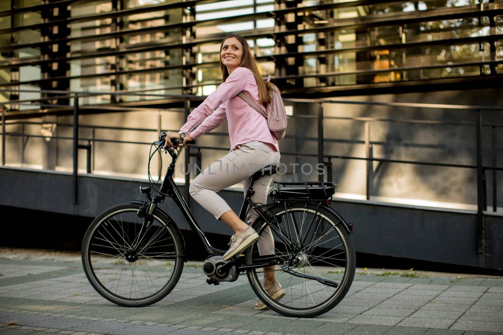 Young woman riding e bike in urban enviroment at sunny day