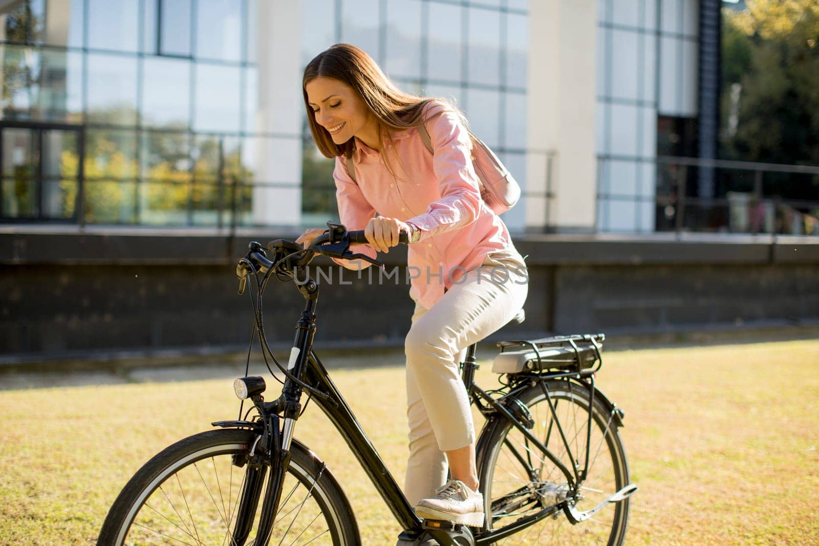 Young woman riding e bike in urban enviroment at sunny day