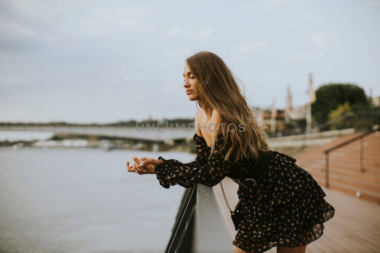 Pretty young long hair brunette woman standing on the riverside