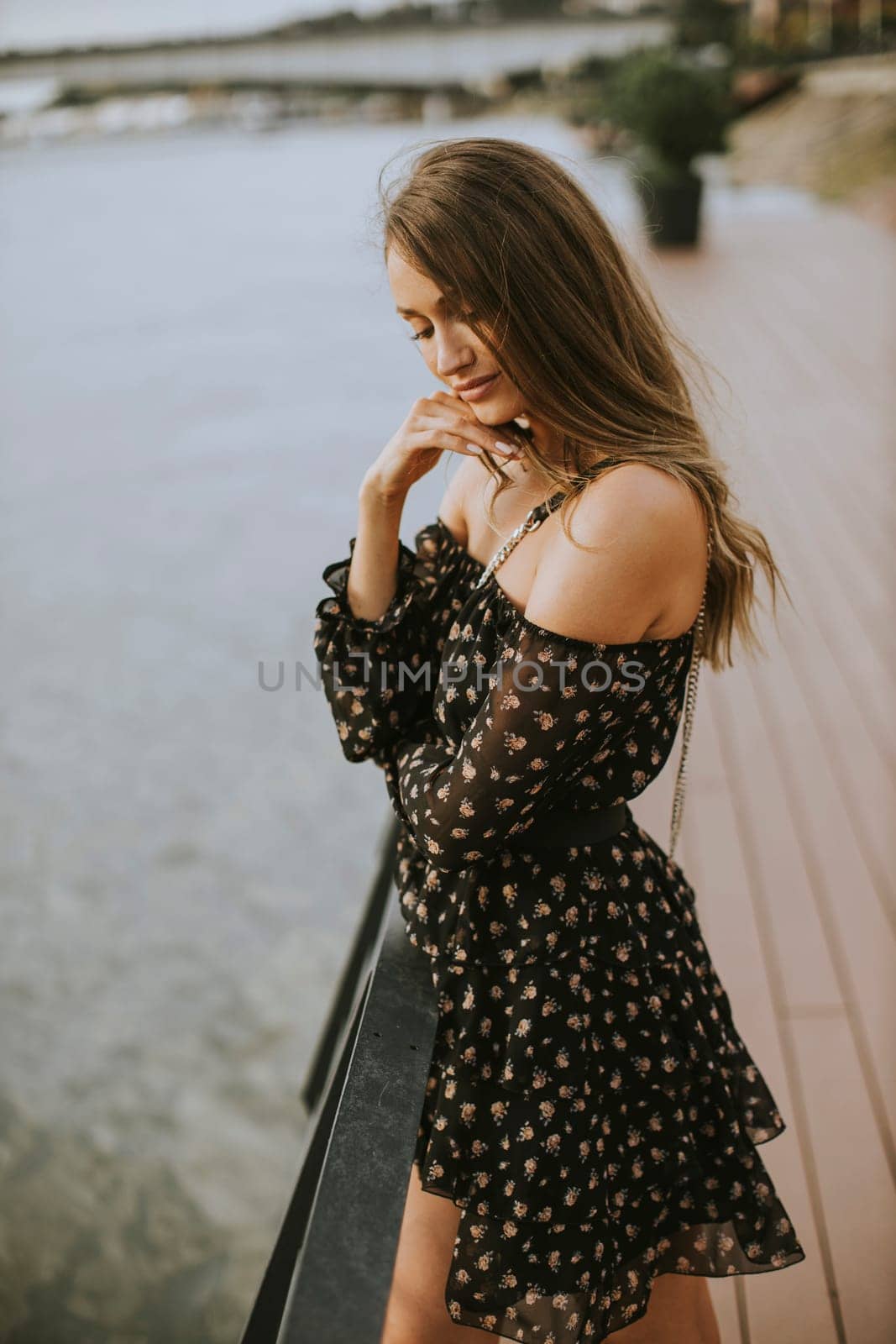 Pretty young long hair brunette woman standing on the riverside