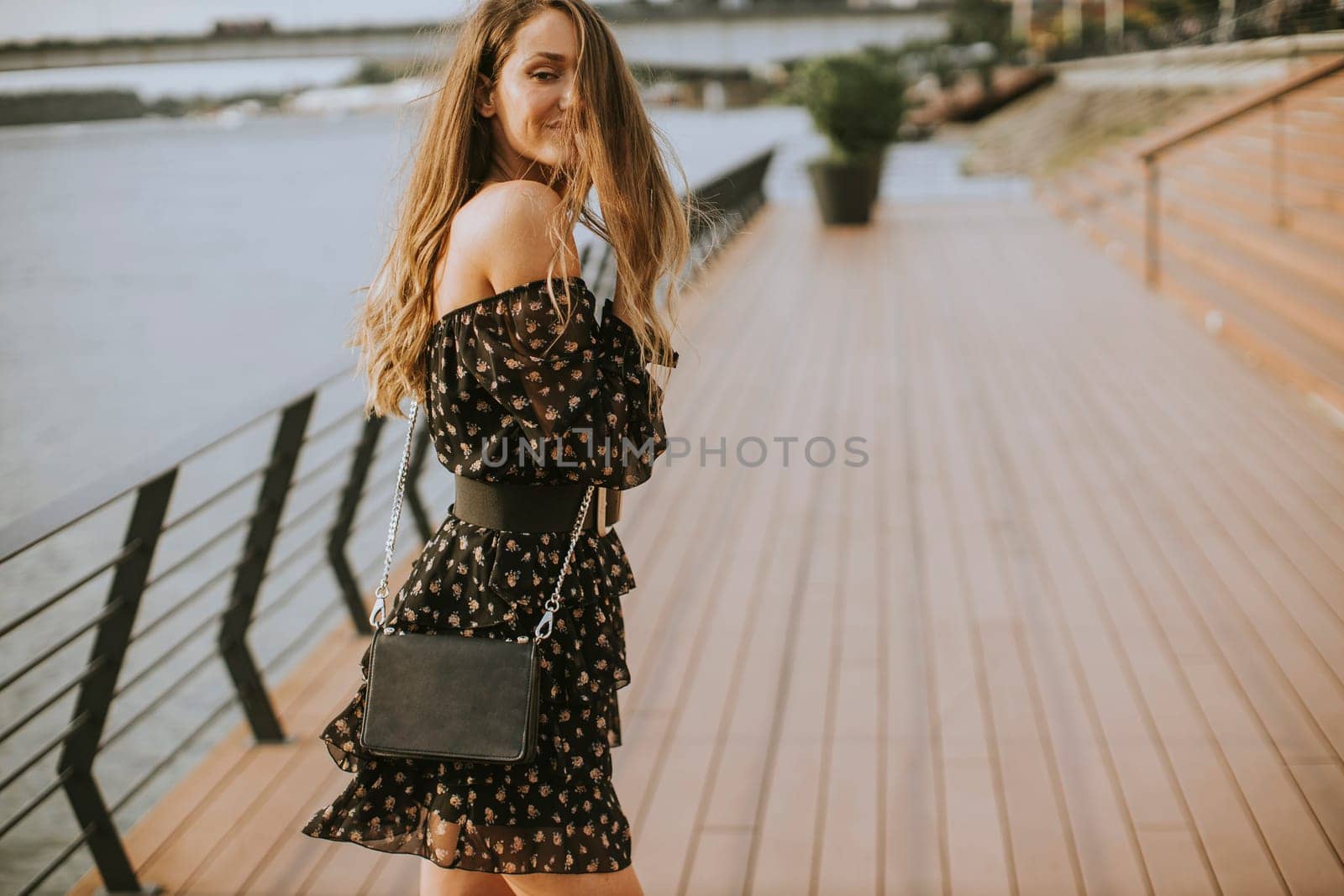 Pretty young long hair brunette woman walking on the riverside