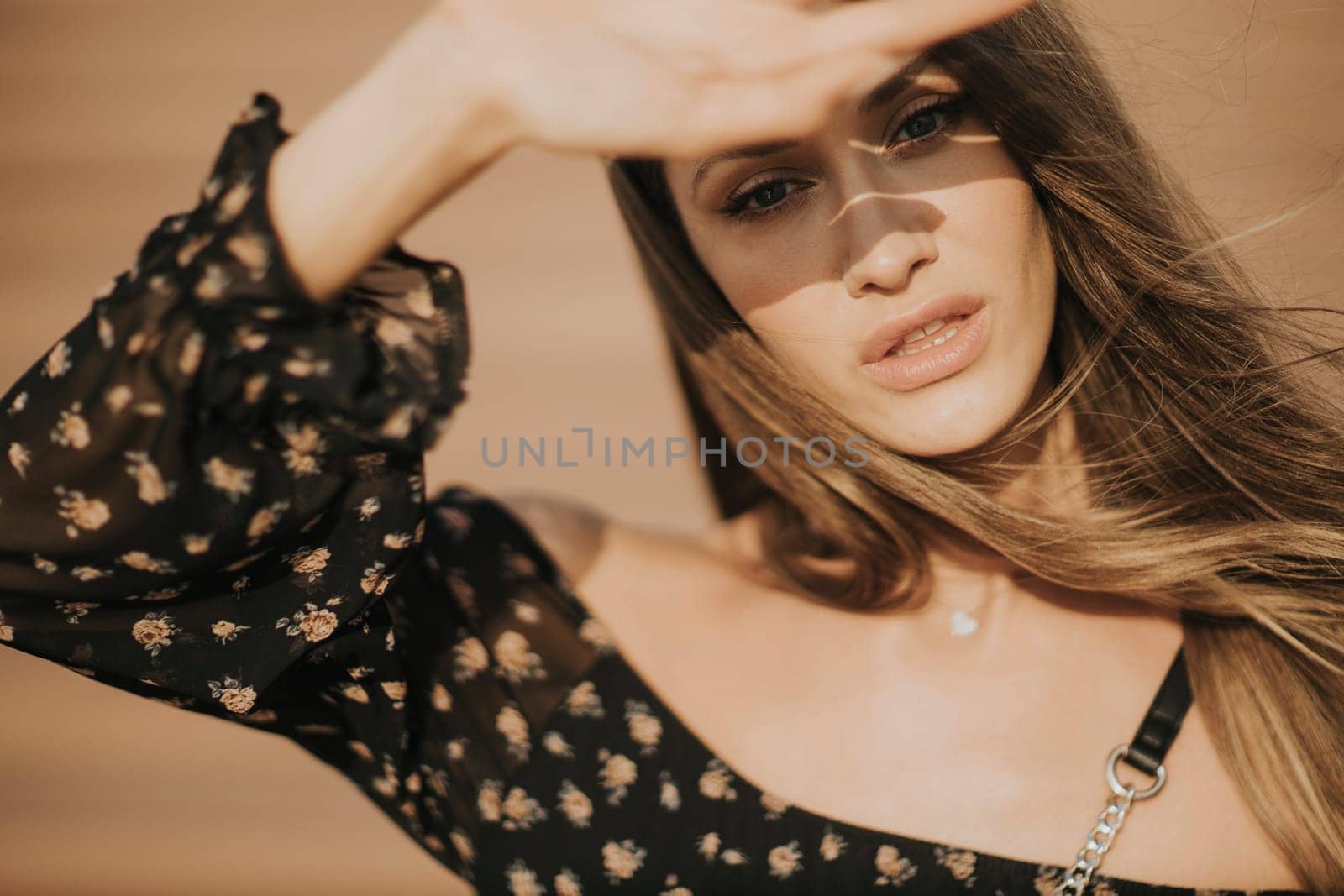 Outdoor portrait of sensual long hair brunette woman covering her face with hand from sunlight