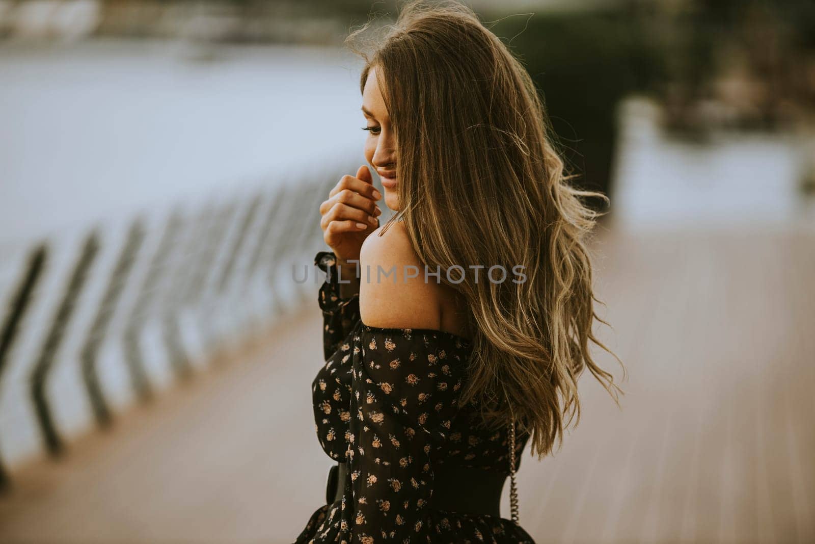 Pretty young long hair brunette woman walking on the riverside